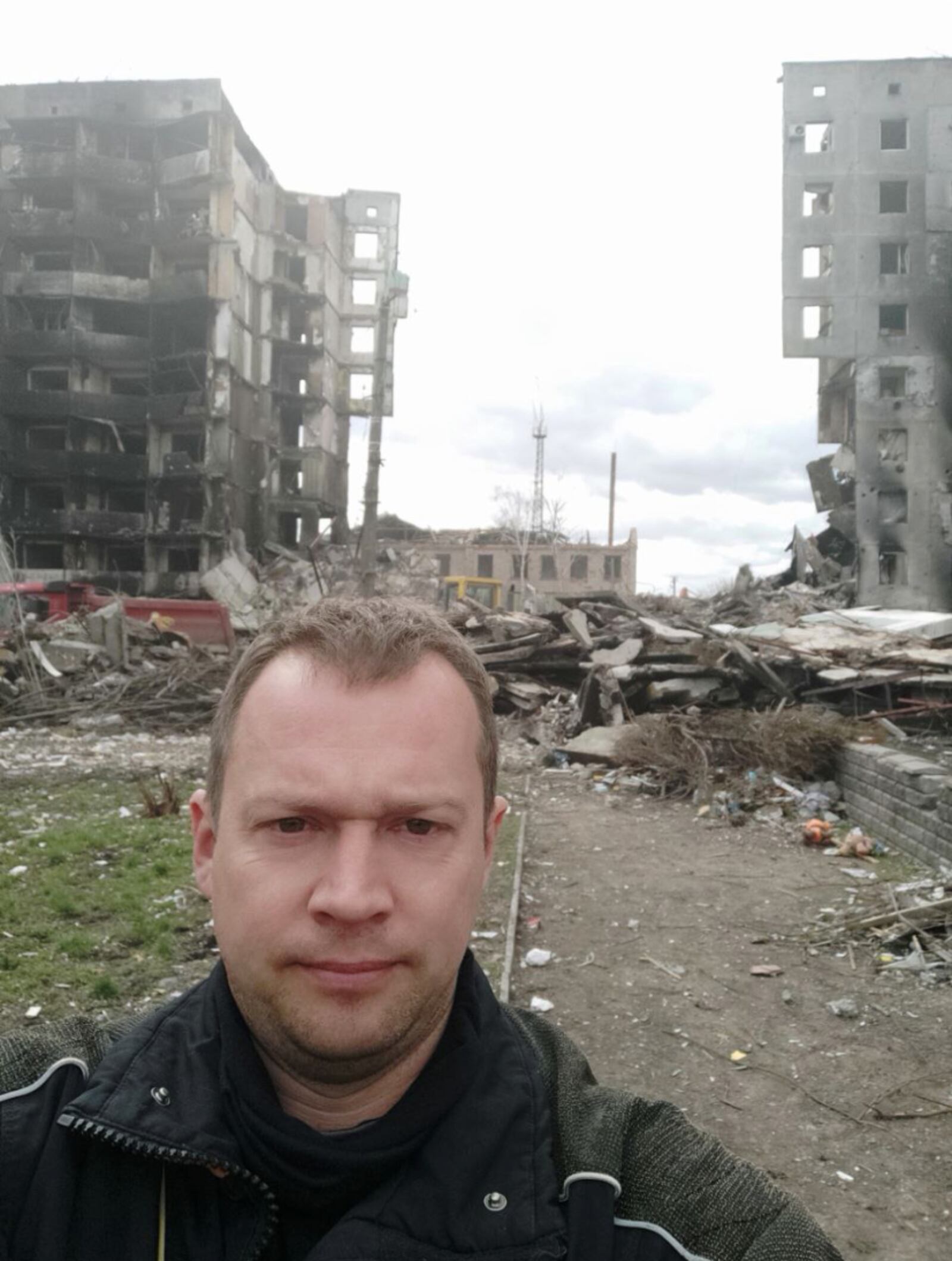 Kostya Vikulkin is front of a high-rise apartment building split in two by Russian missiles. CONTRIBUTED