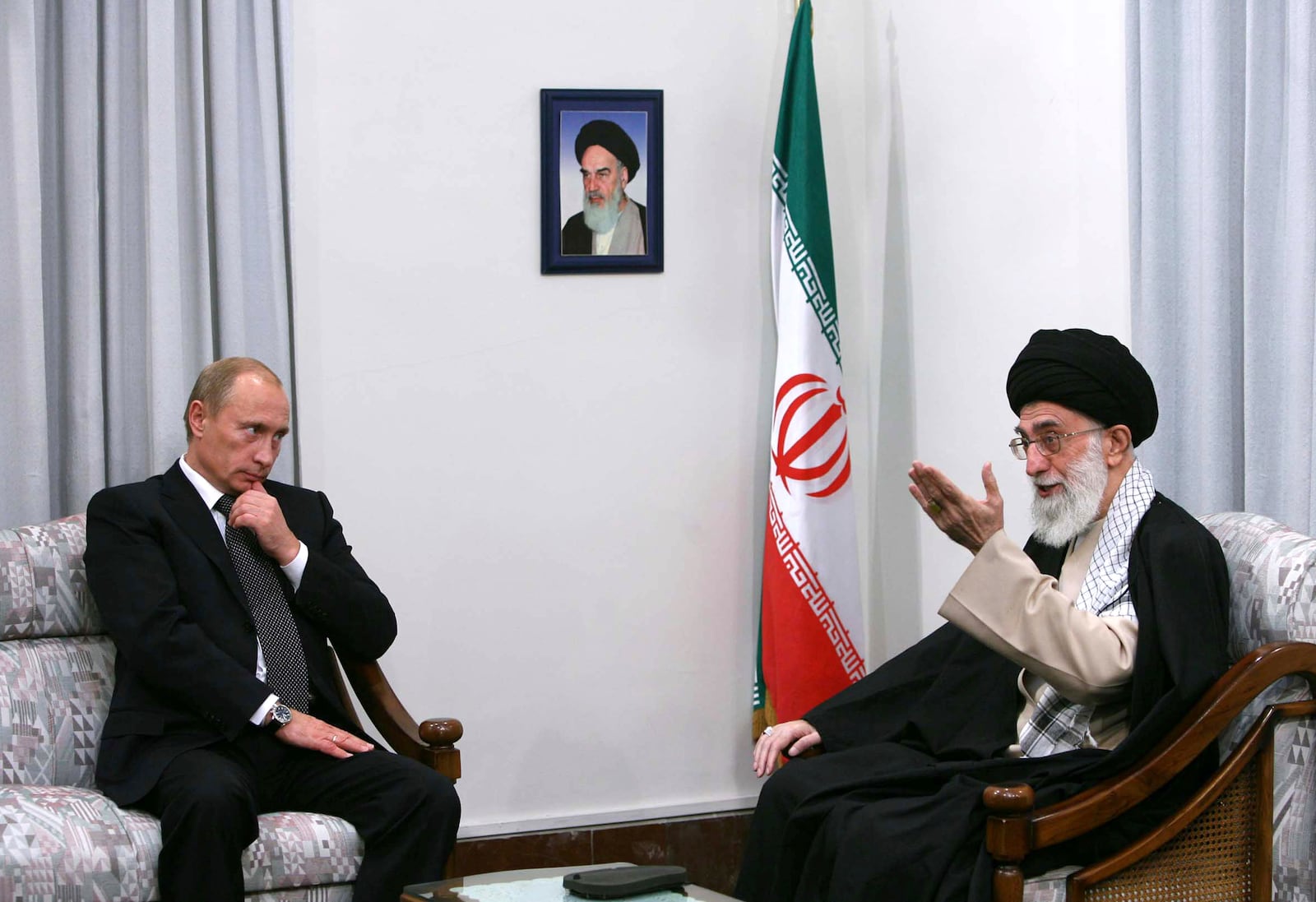 FILE - Under a picture of the late revolutionary founder Ayatollah Ruhollah Khomeini, Iranian Supreme Leader Ayatollah Ali Khamenei, right, talks with Russian President Vladimir Putin during a meeting in Tehran, Iran, on Oct. 16, 2007. (Sajjad Safari/Mehr News Agency via AP, File)