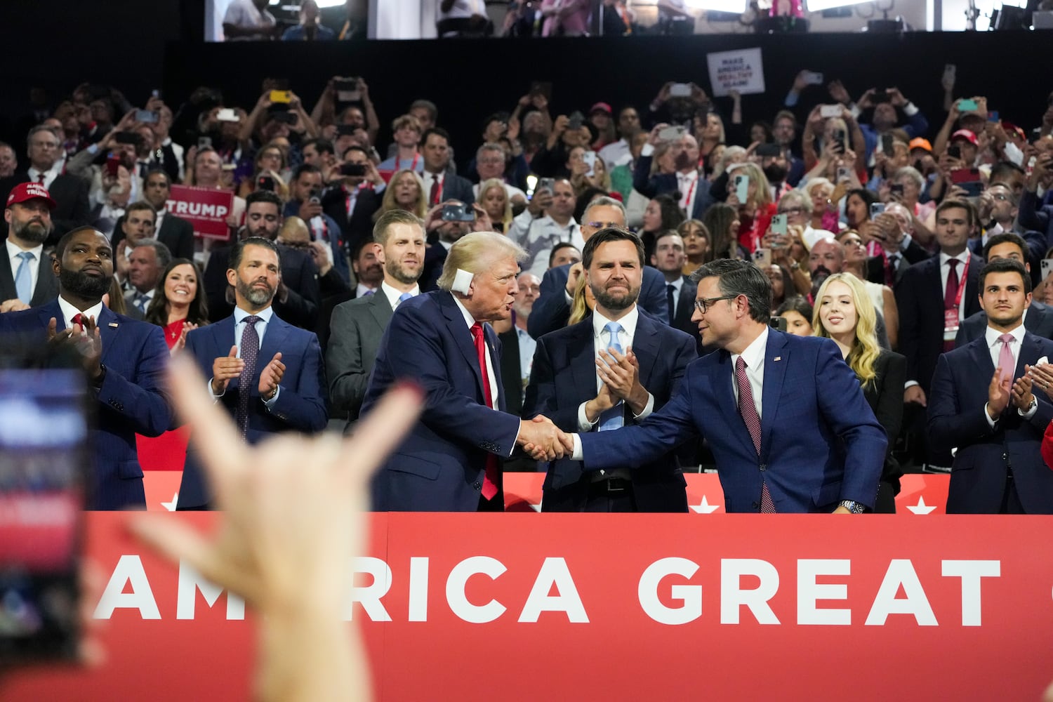 
                        Former President Donald Trump shakes hands with House Speaker Mike Johnson (R-La.) as they stand with  Sen. JD Vance (R-Ohio) on the first night of the Republican National Convention at the Fiserv Forum in Milwaukee, Wis., on Monday, July 15, 2024. Former President Trump announced his running mate, Vance, as the Republican convention kicked off on Monday. Republicans then formally put Trump and Vance at the top of their ticket.  (Todd Heisler/The New York Times)
                      