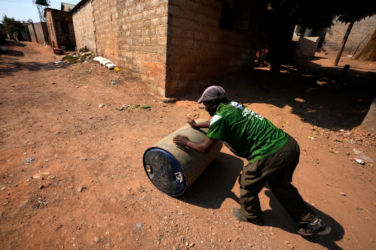 Moses Mngumi rolls a drum with water through the street to his home at Bauleni Township in Lusaka, Zambia, Tuesday, Sept. 17, 2024. (AP Photo/Themba Hadebe)