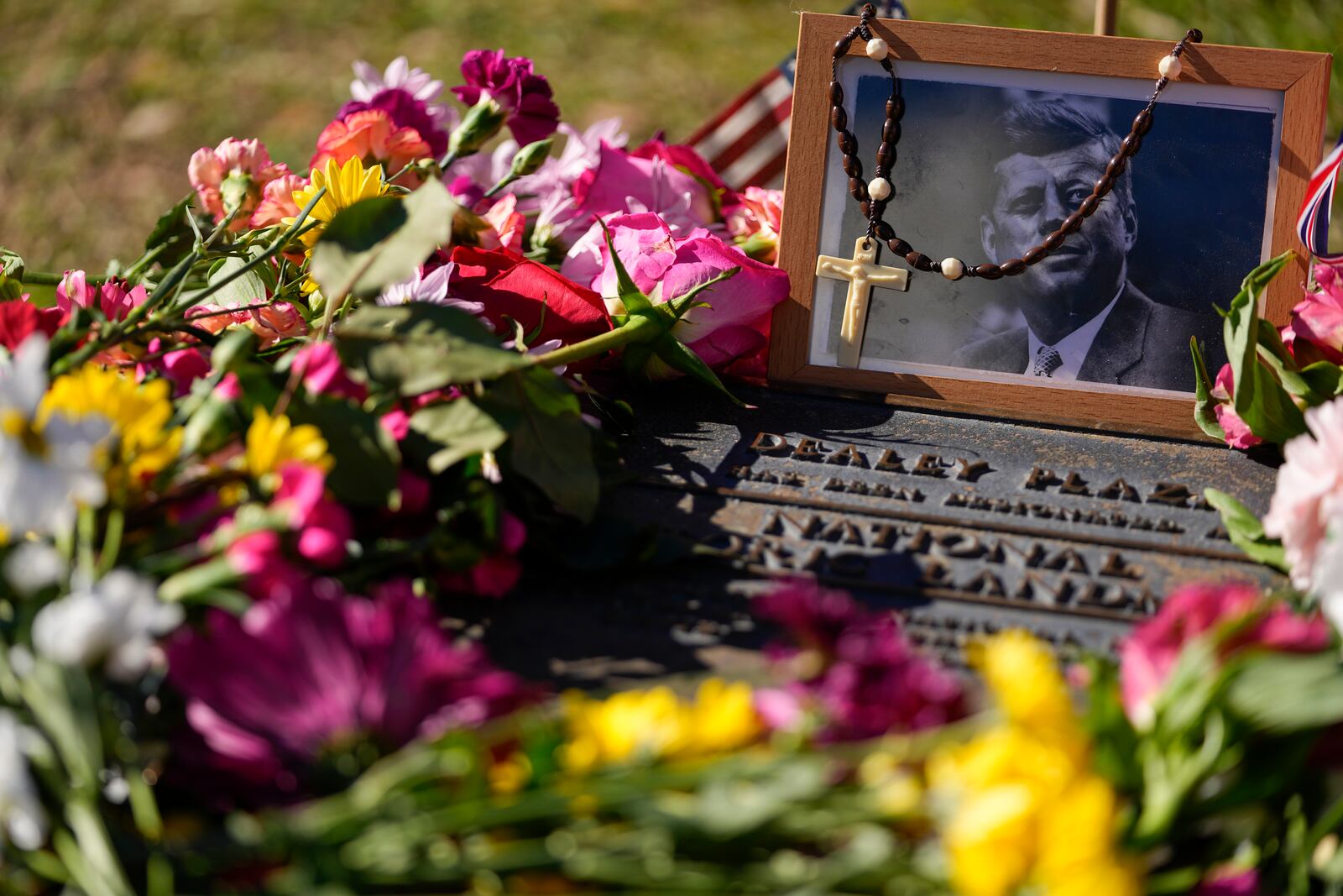 FILE - A rosary covers a photograph of President John F. Kennedy at a marker along Elm Street, where the former president was assassinated, as flowers adorn the memorial on the 60th anniversary of his assassination, Nov. 22, 2023, in Dallas. (AP Photo/Julio Cortez, File)