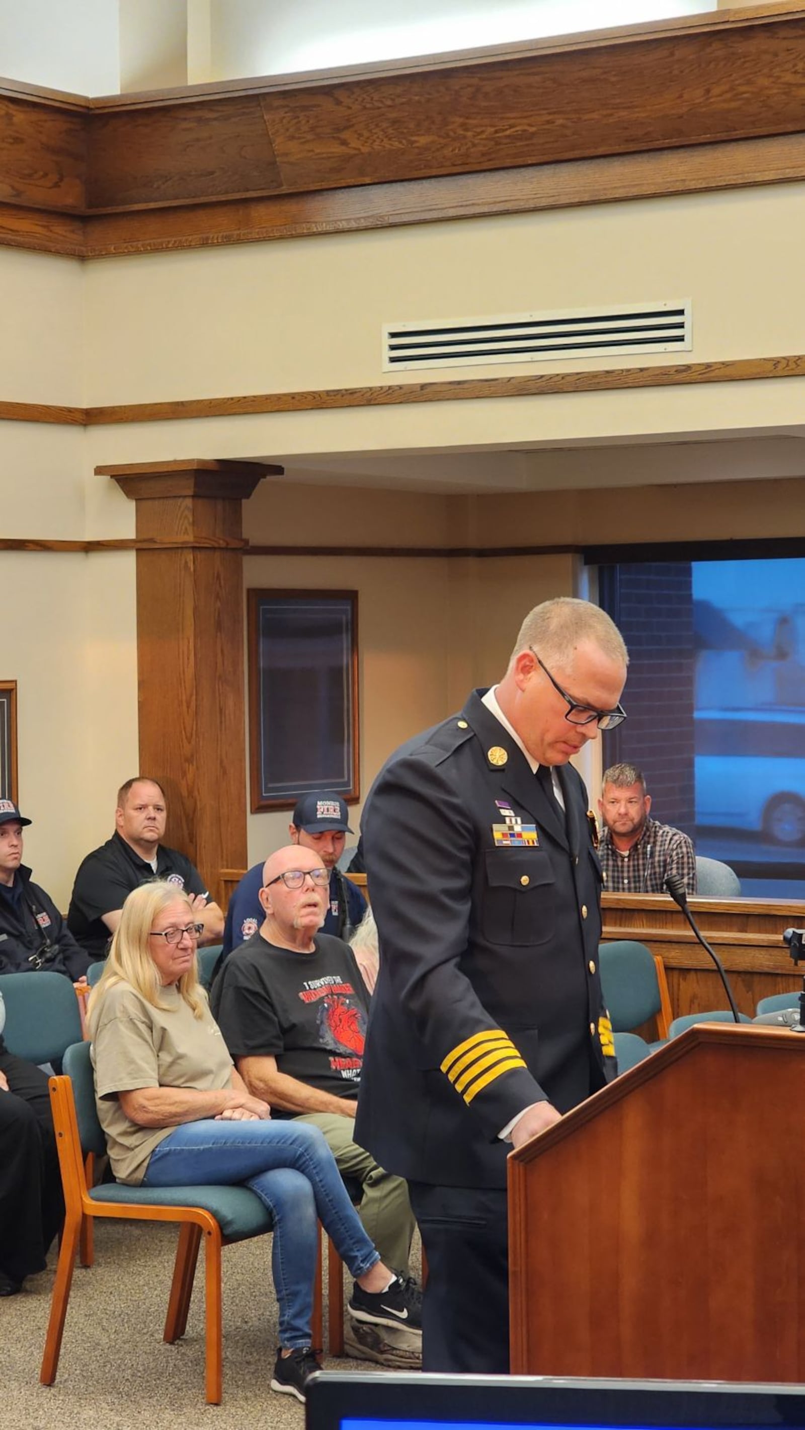 Matt Grubbs, Monroe's assistant fire chief, talks Tuesday night during a City Council meeting about how a woman who performed CPR and firefighters saved Richard Kohl's life on Aug. 12. Kohl and his sister-in-law Angie Boggs, who performed CPR, are sitting behind Grubbs. SUBMITTED PHOTO