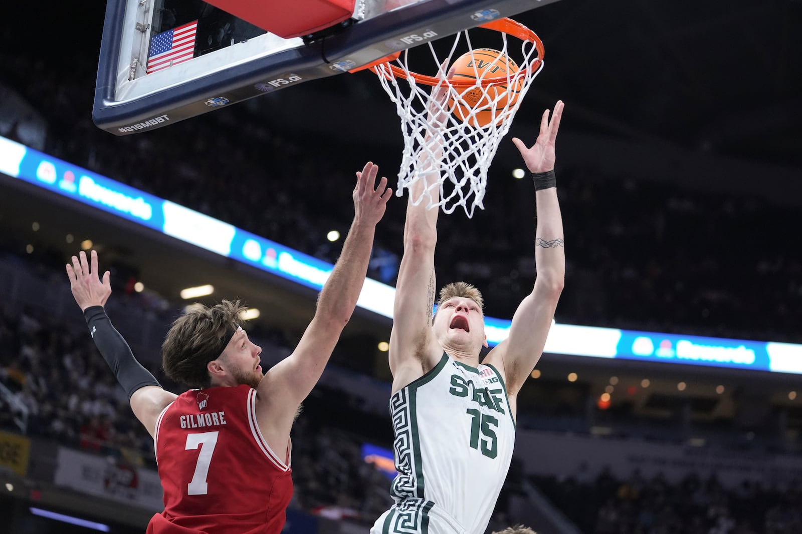 Michigan State center Carson Cooper (15) shoots on Wisconsin forward Carter Gilmore (7) during the first half of an NCAA college basketball game in the semifinals of the Big Ten Conference tournament in Indianapolis, Saturday, March 15, 2025. (AP Photo/Michael Conroy)