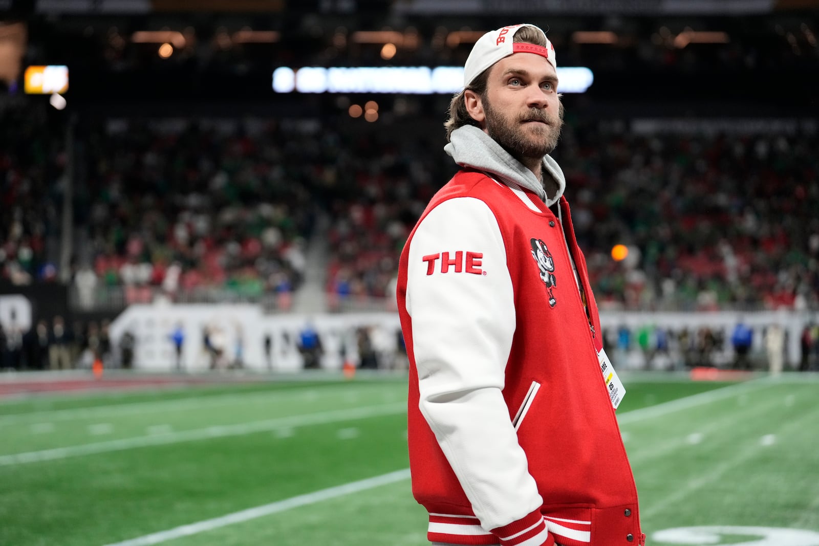 Philadelphia Phillies First Baseman Bryce Harper watches during warm ups before the College Football Playoff national championship game between Ohio State and Notre Dame Monday, Jan. 20, 2025, in Atlanta. (AP Photo/Brynn Anderson)