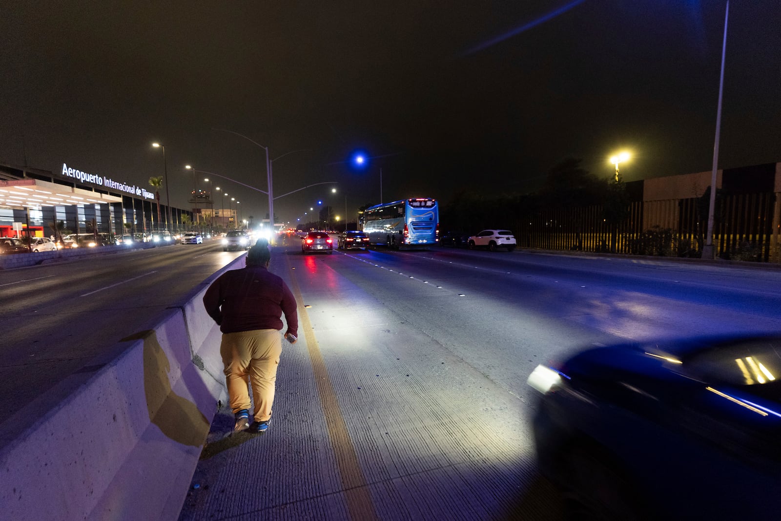 Martha Rosales walks along a street to the Tijuana airport to pick up an arriving migrant who will stay at Rosales' home while waiting an appointment to apply for asylum in the United States through the CBP One app Wednesday, Aug. 28, 2024, in Tijuana, Mexico. (AP Photo/Gregory Bull)