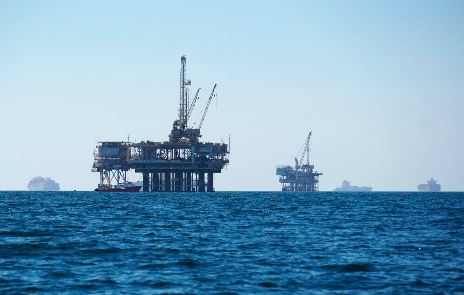 FILE - Cargo vessels are seen anchored offshore, sharing space with oil platforms, before heading into the Los Angeles-Long Beach port on Oct. 5, 2021. (AP Photo/Eugene Garcia, File)