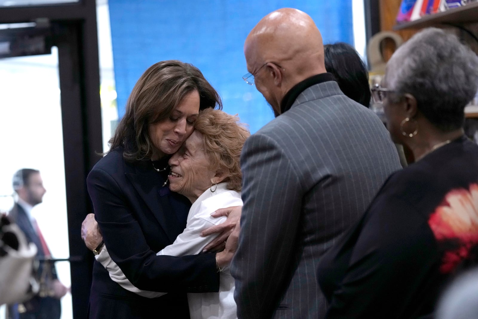 Democratic presidential nominee Vice President Kamala Harris, from left, hugs Ann Hughes as her son State Sen. Vincent Hughes, D-Philadelphia, looks on at Hakim's Bookstore and Gift Shop during a campaign stop, Sunday, Oct. 27, 2024, in Philadelphia. (AP Photo/Susan Walsh)