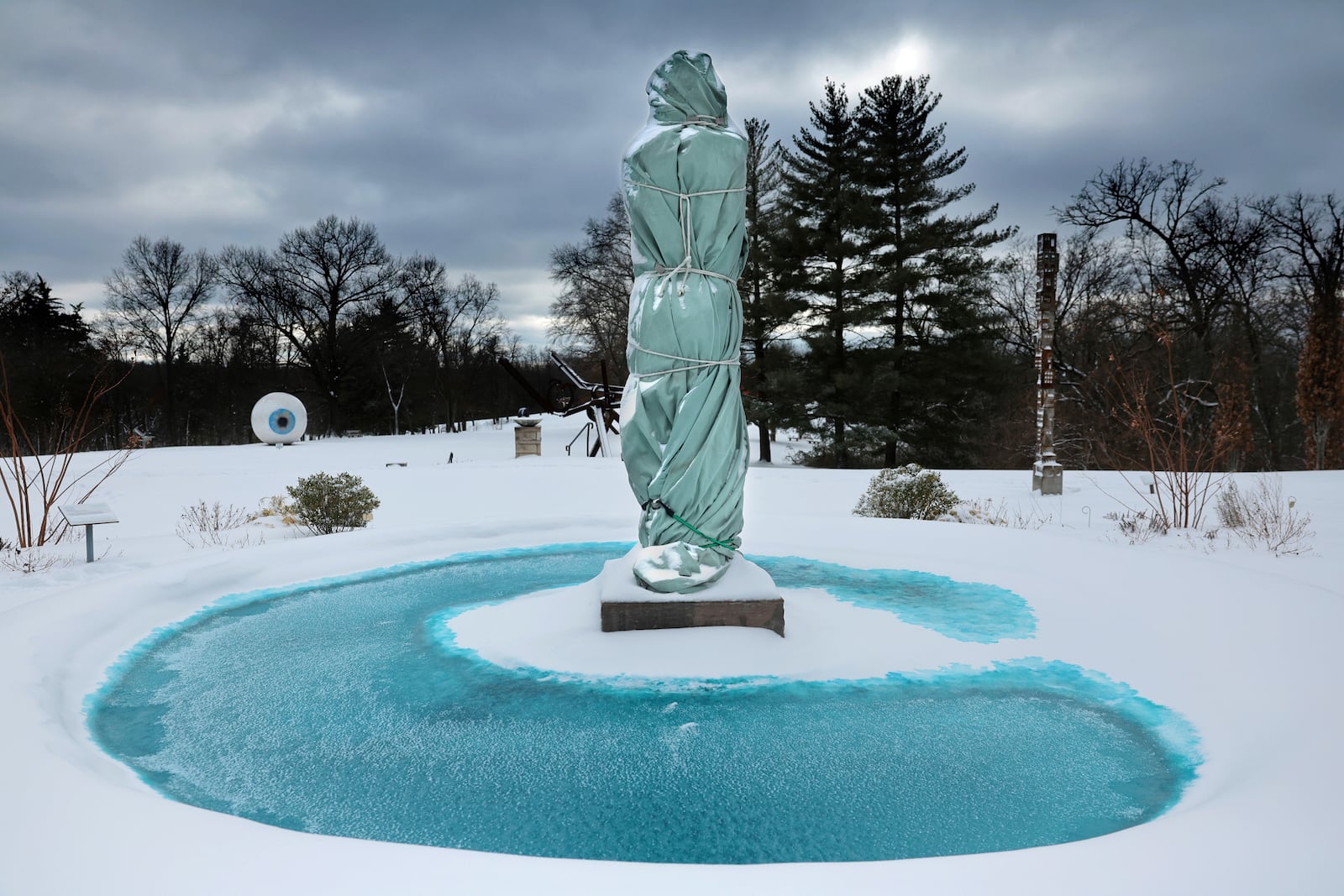 "Aurelia Roma", a 1994 Italian marble sculpture by Manuel Neri, is wrapped for the season as she stands in the pool of the Estate House terrace surrounded by snow at Laumeier Sculpture Park in Sunset Hills, Mo. on Monday, Jan. 6, 2025. (Robert Cohen/St. Louis Post-Dispatch via AP)