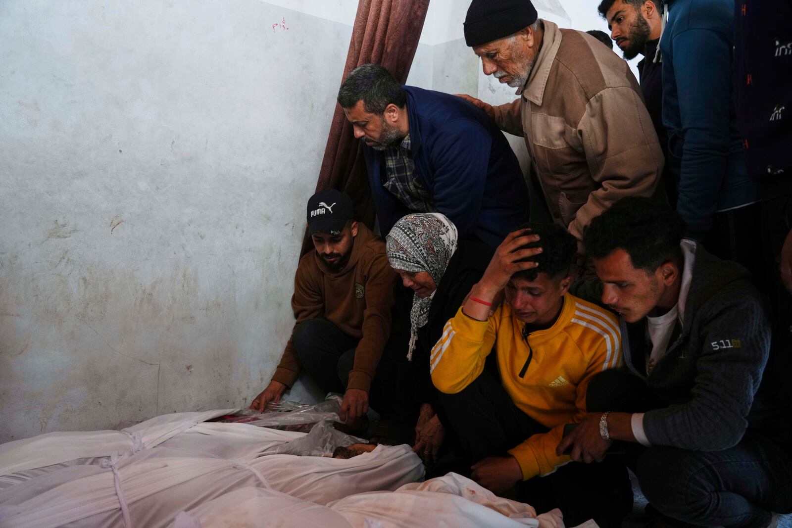 Palestinians mourn over the bodies of their relatives killed by an Israeli airstrike in the Netzarim corridor, at the Al-Ahli Hospital in Gaza City on Tuesday, March 11, 2025. (AP Photo/(AP Photo/Jehad Alshrafi)