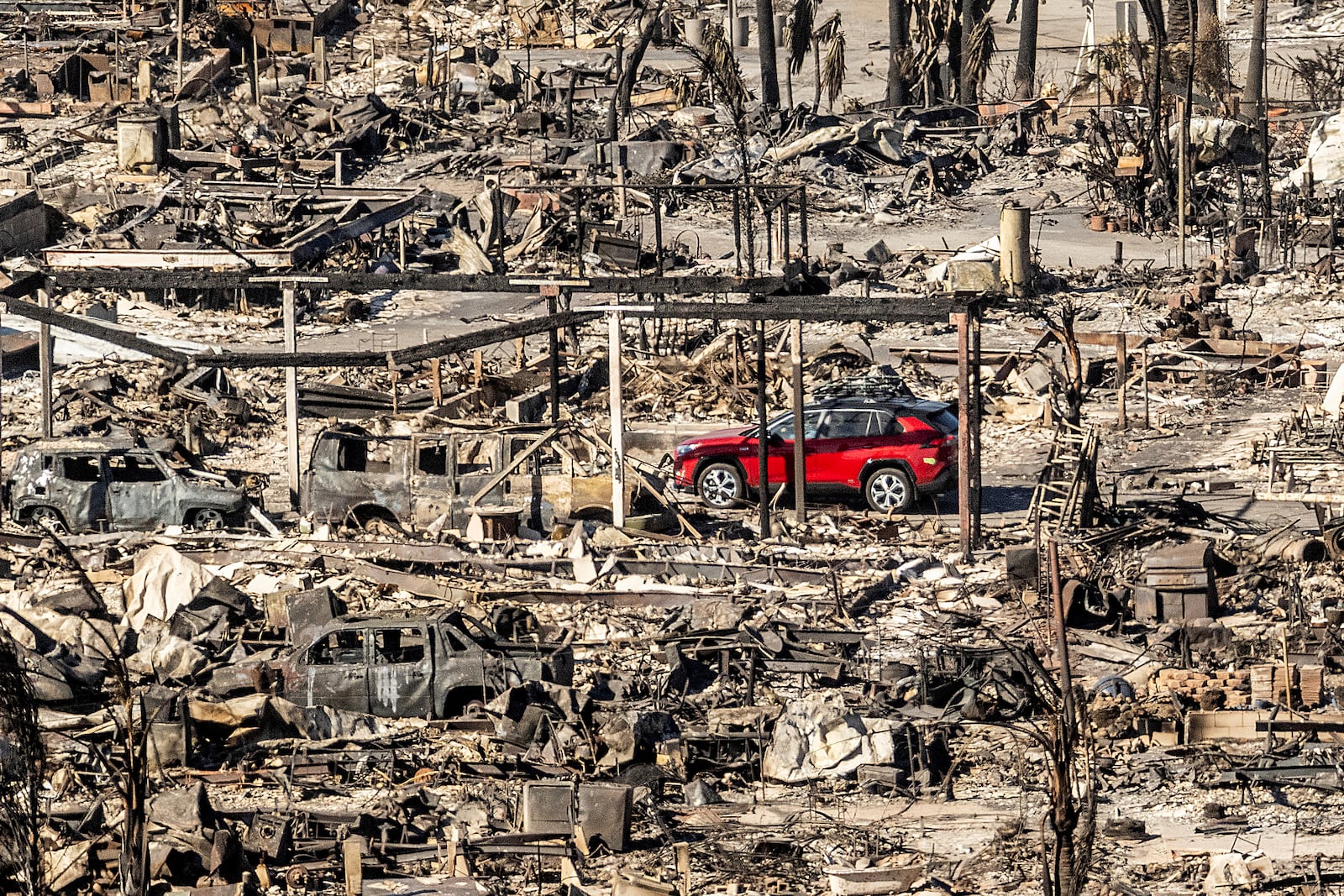 A car drives past homes and vehicles destroyed by the Palisades Fire at the Pacific Palisades Bowl Mobile Estates on Sunday, Jan. 12, 2025, in Los Angeles. (AP Photo/Noah Berger)