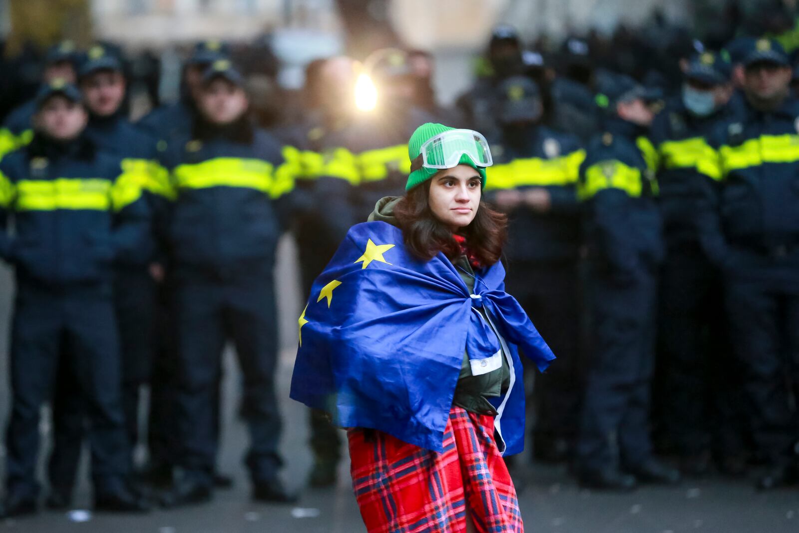 A woman holds an EU flag in front of police blocking the entrance of the Parliament's building during a rally to demand new parliamentary elections in the country, in Tbilisi, Georgia, Monday, Nov. 25, 2024. (AP Photo/Zurab Tsertsvadze)