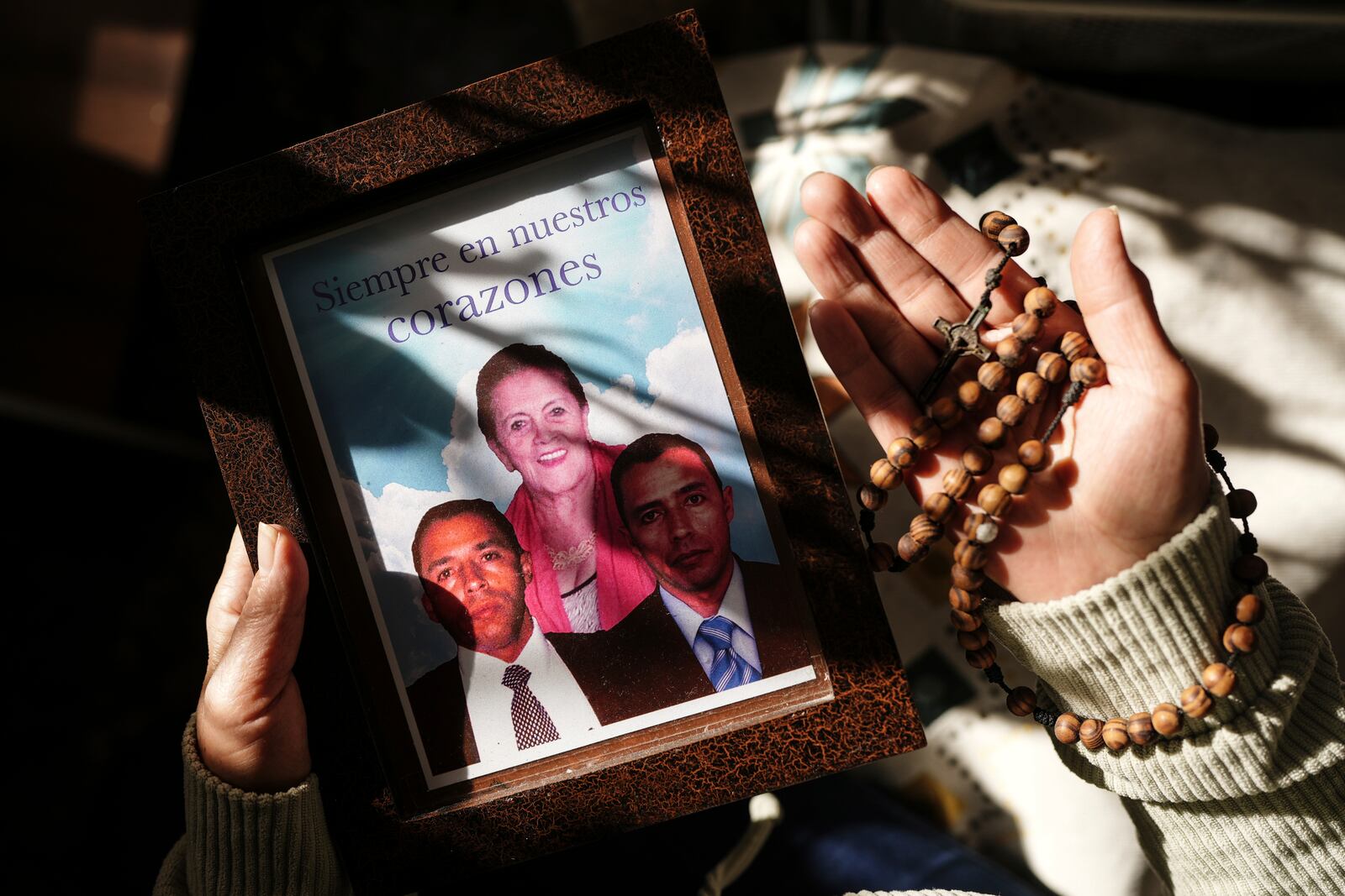 Maria Fenix shows a photo of her missing brothers while holding a rosary during an interview in Bogota, Colombia, Monday, Nov. 4, 2024. The twin brothers, Alexander and Henry, vanished on their way to a business meeting in 2007. (AP Photo/Ivan Valencia)