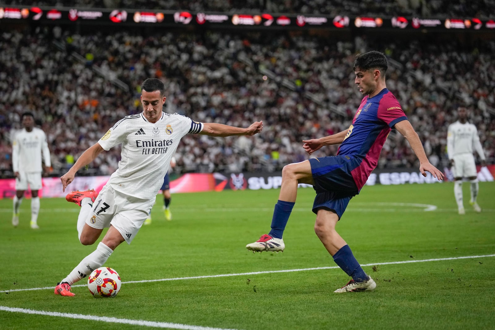 Real Madrid's Lucas Vazquez, left, challenges for the ball with Barcelona's Pedri during the Spain Super Cup final soccer match between Real Madrid and Barcelona at King Abdullah Stadium in Jeddah, Saudi Arabia, Sunday, Jan. 12, 2025. (AP Photo/Altaf Qadri)