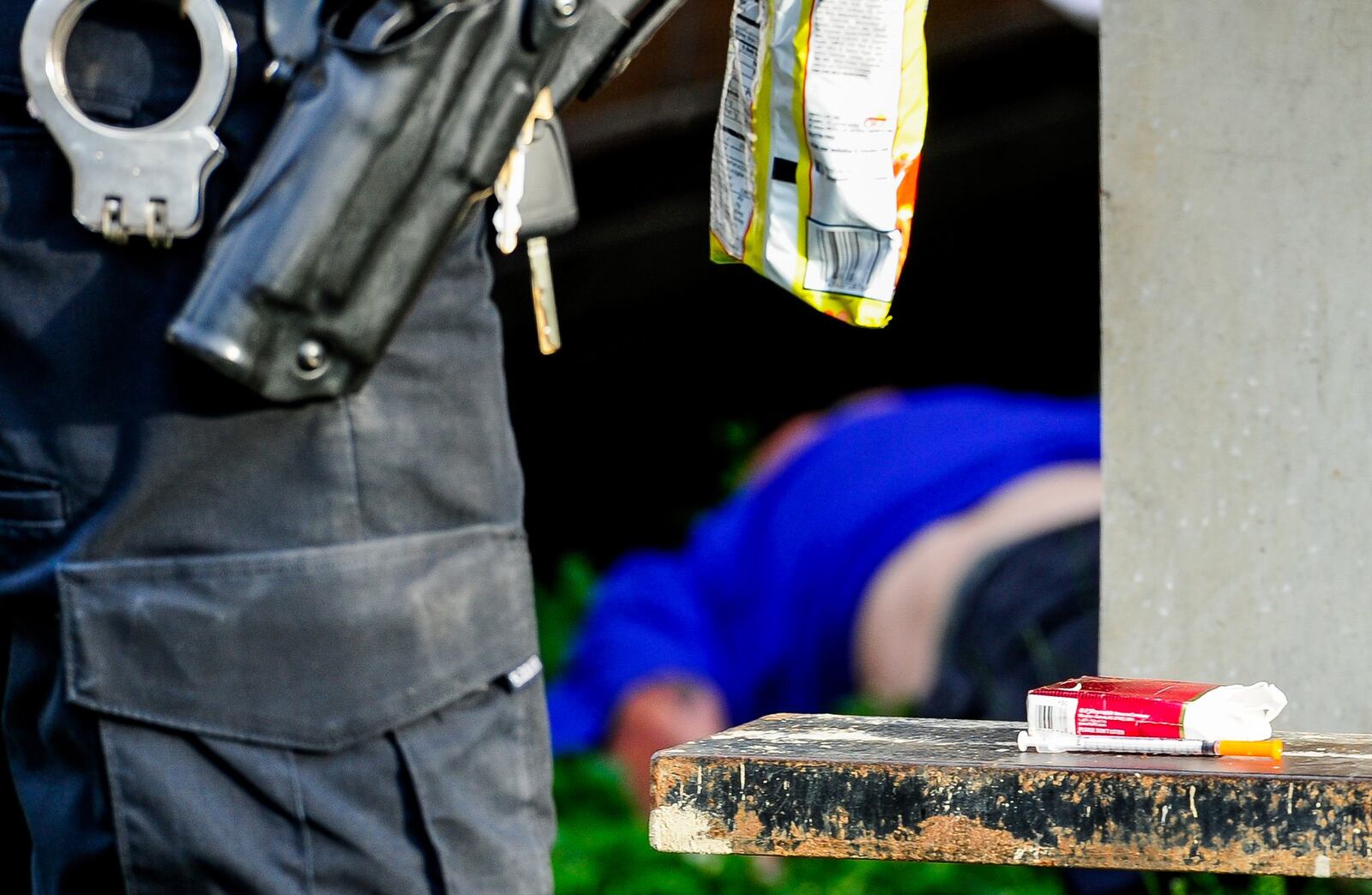 Middletown police officers secure property, including a needle, after responding to a drug overdose behind the Midd-Town Carry Out on Central Avenue Monday, June 26. NICK GRAHAM/STAFF