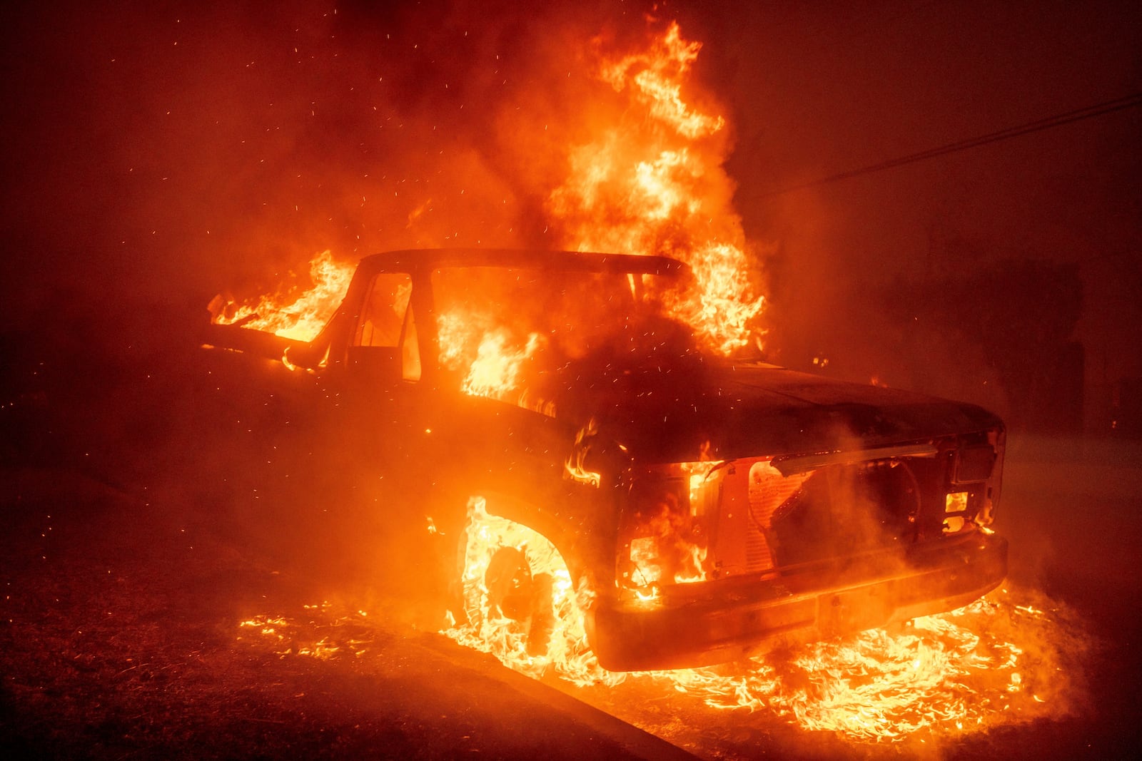 The Eaton Fire burns a vehicle Wednesday, Jan. 8, 2025, in Altadena, Calif. (AP Photo/Ethan Swope)