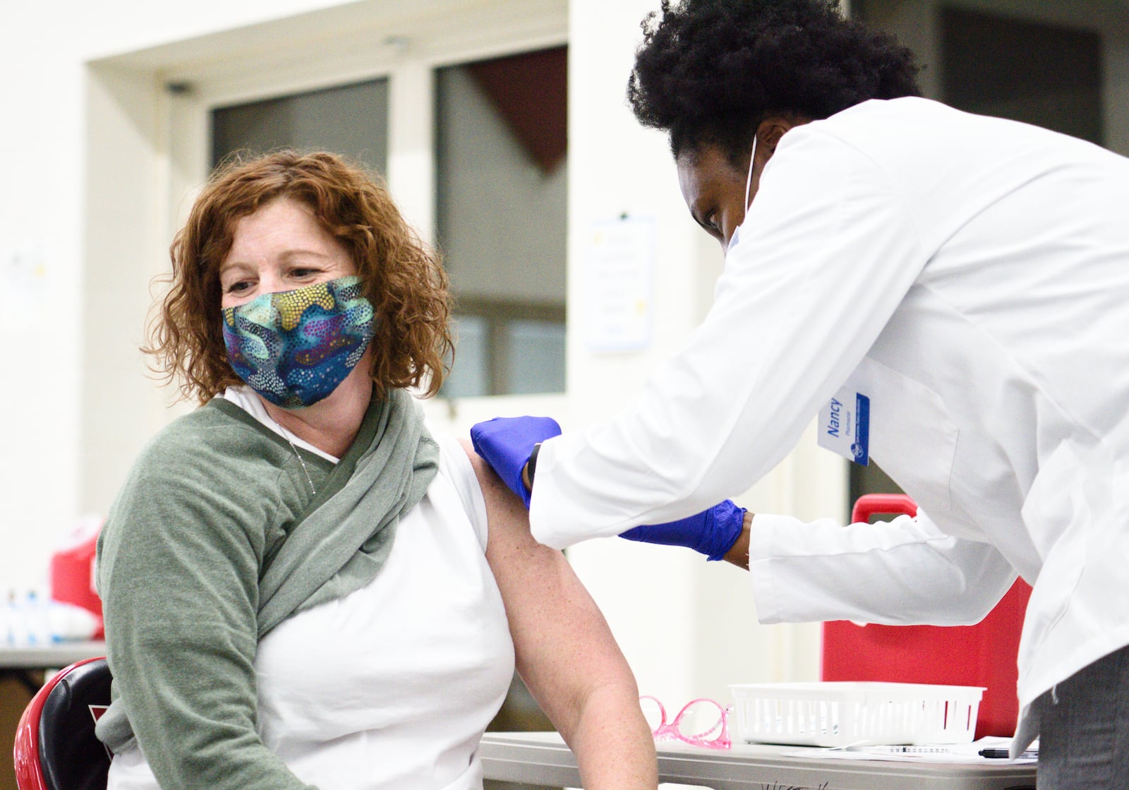 Lakota schools employee Amy Powell gets her Covid-19 vaccine administered by Kroger pharmacist Nancy Adomako Wednesday, February 3, 2021 at Lakota West High School in West Chester Township. NICK GRAHAM / STAFF