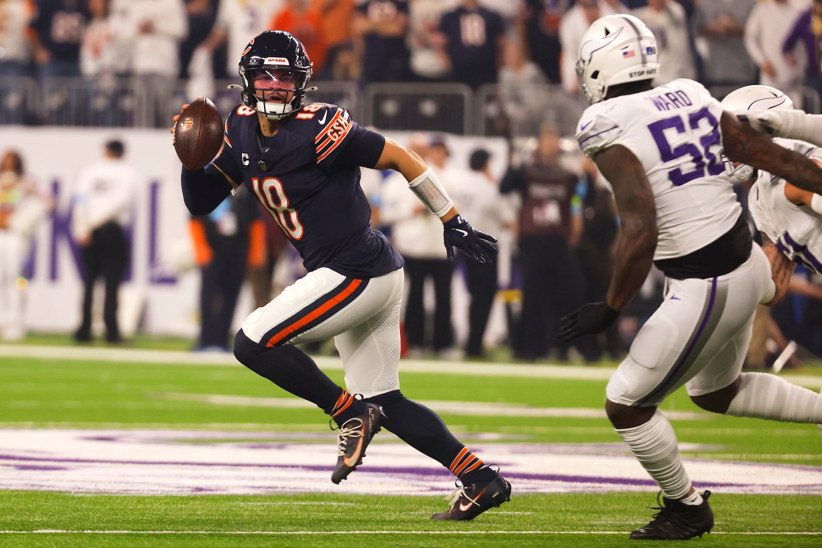 Chicago Bears quarterback Caleb Williams (18) runs from Minnesota Vikings linebacker Jihad Ward (52) during the first half of an NFL football game, Monday, Dec. 16, 2024, in Minneapolis. (AP Photo/Bruce Kluckhohn)