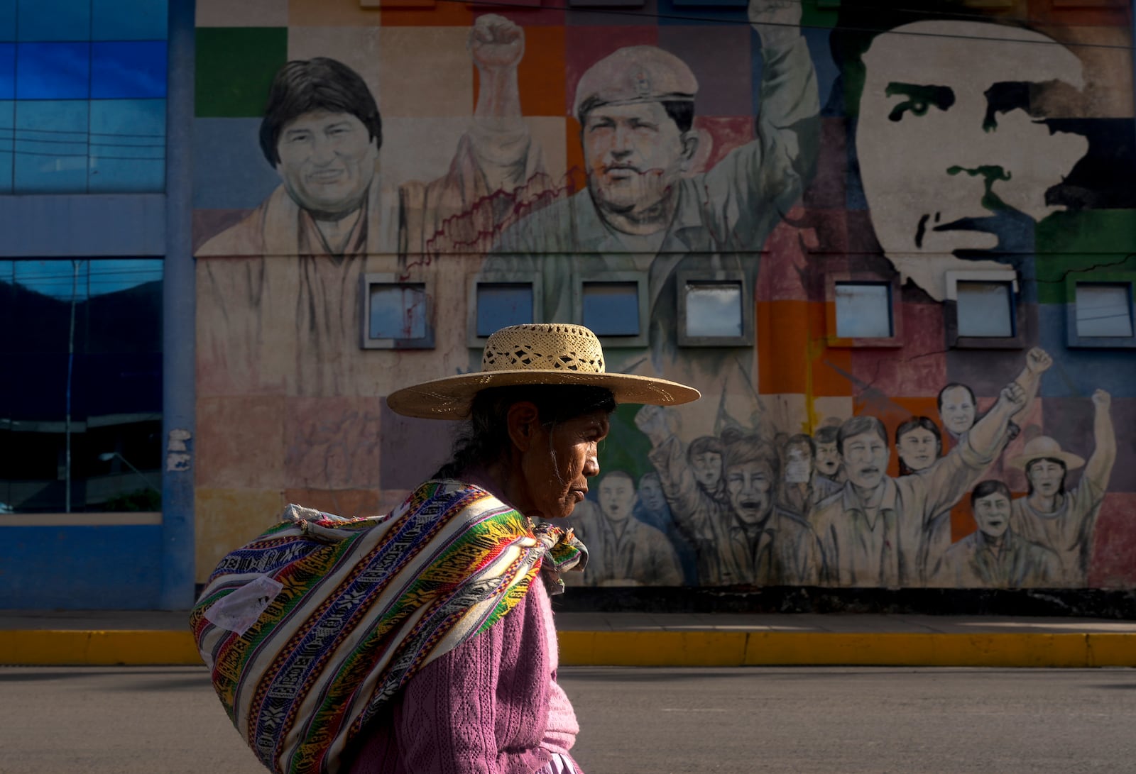 FILE - A woman walks past a mural featuring socialist leaders, from left; former Bolivian President Evo Morales, late Venezuelan President Hugo Chavez and revolutionary Ernesto "Che: Guevara, at the bus terminal in Sacaba, Bolivia, Nov. 20, 2024. (AP Photo/Juan Karita, File)