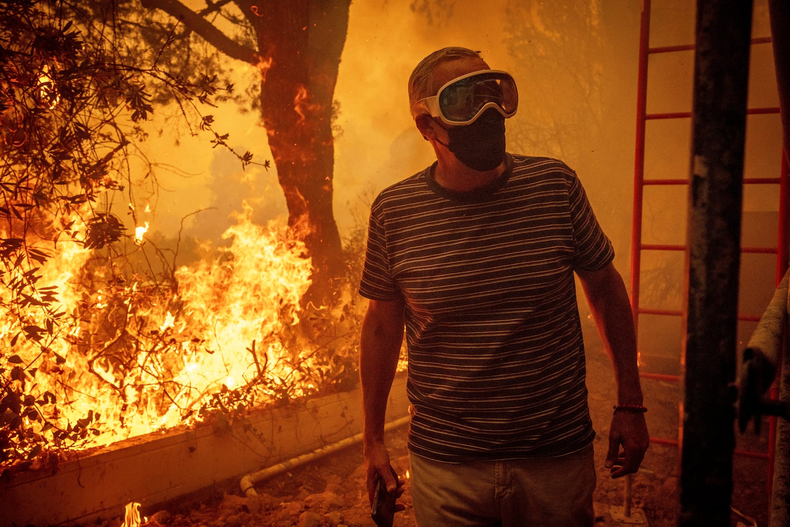 Will Adams watches as flames from the Palisades Fire close in on his property in the Pacific Palisades neighborhood of Los Angeles, Tuesday, Jan. 7, 2025. (AP Photo/Ethan Swope)