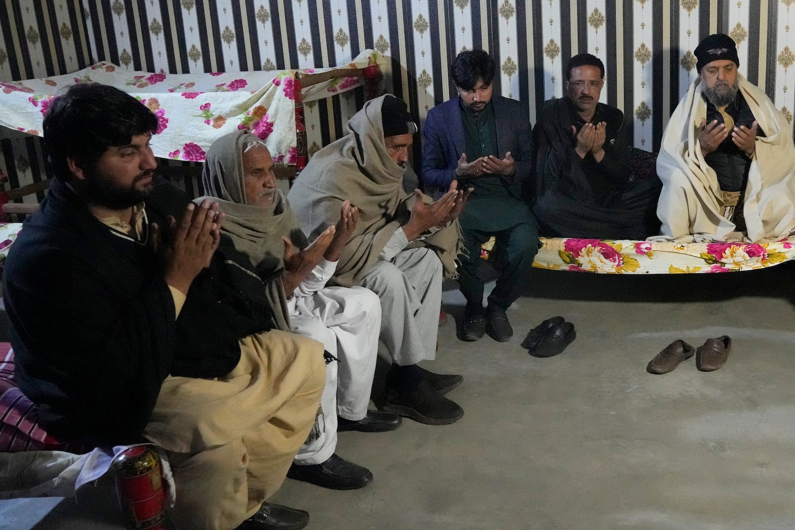 Ahsan Shahzad, father of Suffian Ali, one of the victims of a migrant boat that capsized in West Africa's Atlantic coastline, is consoled by relatives at his home in the village of Dhola, Lalamusa district, Pakistan, Friday, Jan. 17, 2024. (AP Photo/K.M. Chaudary)