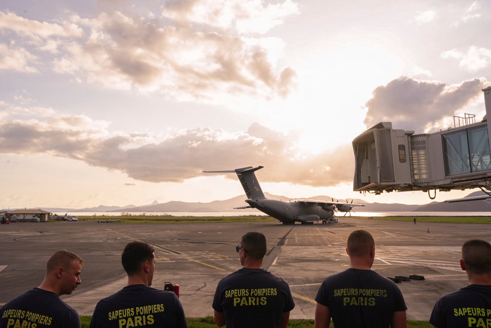 French firemen stand on the tarmac of the airport Wednesday, Dec. 18, 2024 in the French Indian Ocean island of Mayotte. (AP Photo/Adrienne Surprenant)