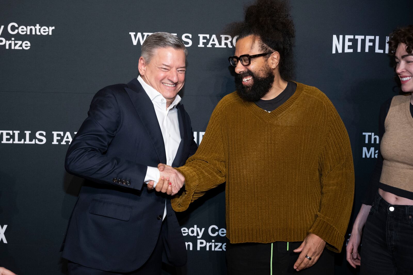 Netflix co-CEO Ted Sarandos, left, shakes hands with Reggie Watts as they arrive at the 25th Annual Mark Twain Prize for American Humor Celebrating Conan O'Brien, Sunday, March 23, 2025, at the Kennedy Center for the Performing Arts in Washington. (AP Photo/Kevin Wolf)