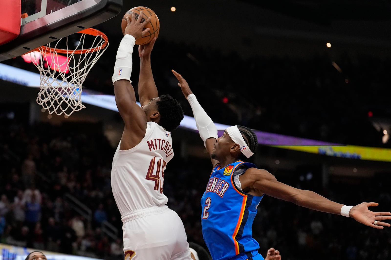 Cleveland Cavaliers guard Donovan Mitchell (45) goes up for a dunk in front of Oklahoma City Thunder guard Shai Gilgeous-Alexander (2) in the first half of an NBA basketball game, Wednesday, Jan. 8, 2025, in Cleveland. (AP Photo/Sue Ogrocki)