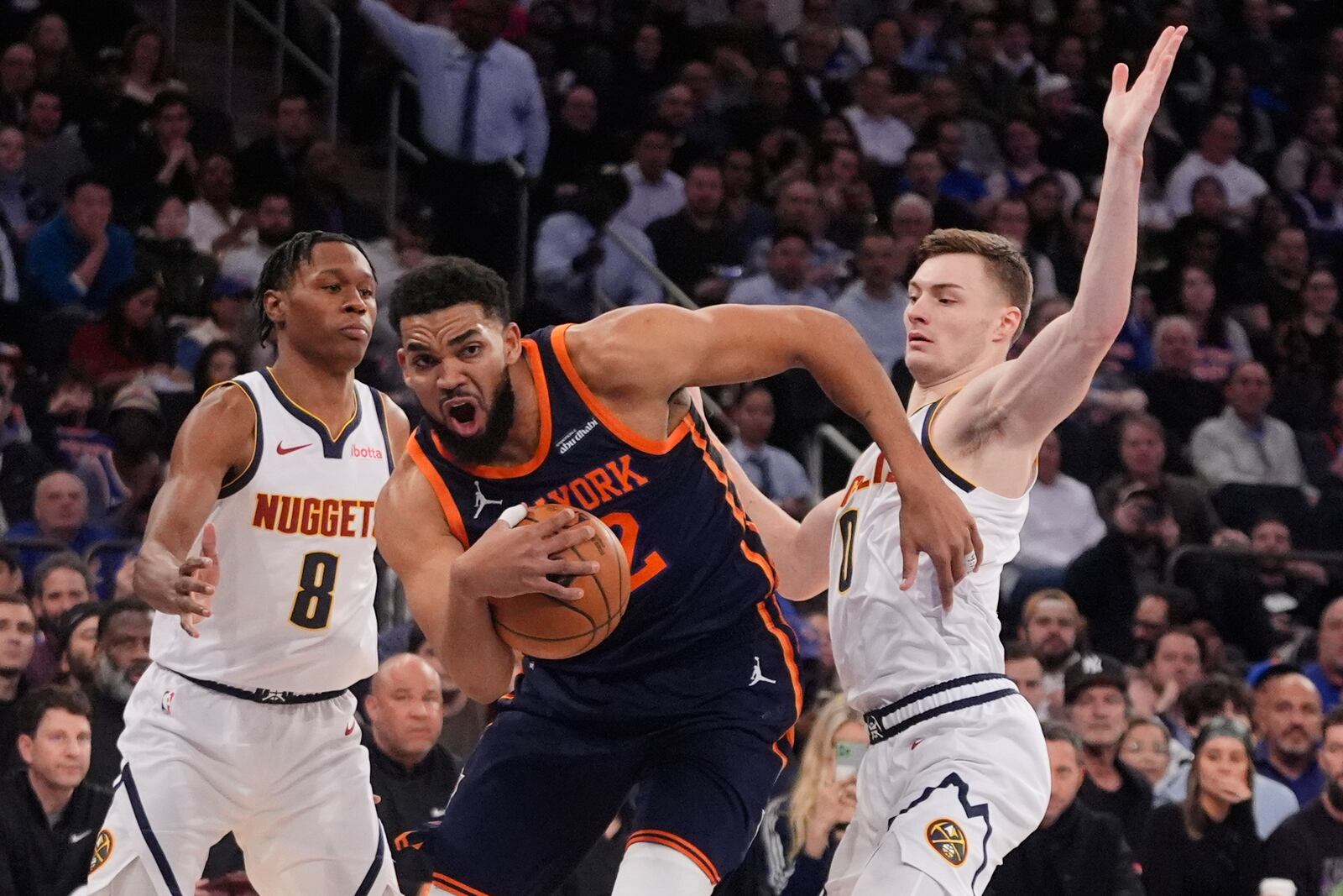 New York Knicks' Karl-Anthony Towns (32) drives past Denver Nuggets' Peyton Watson (8) and Christian Braun (0) during the first half of an NBA basketball game Wednesday, Jan. 29, 2025, in New York. (AP Photo/Frank Franklin II)