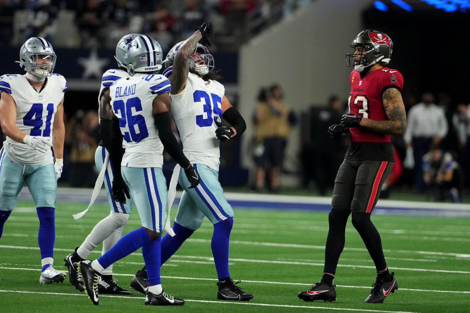 Dallas Cowboys' Marist Liufau (35), DaRon Bland (26), Nick Vigil (41) and others celebrate Liufau's defensive play as Tampa Bay Buccaneers' Mike Evans (13) looks on in the second half of an NFL football game in Arlington, Texas, Sunday, Dec. 22, 2024. (AP Photo/Jeffrey McWhorter)