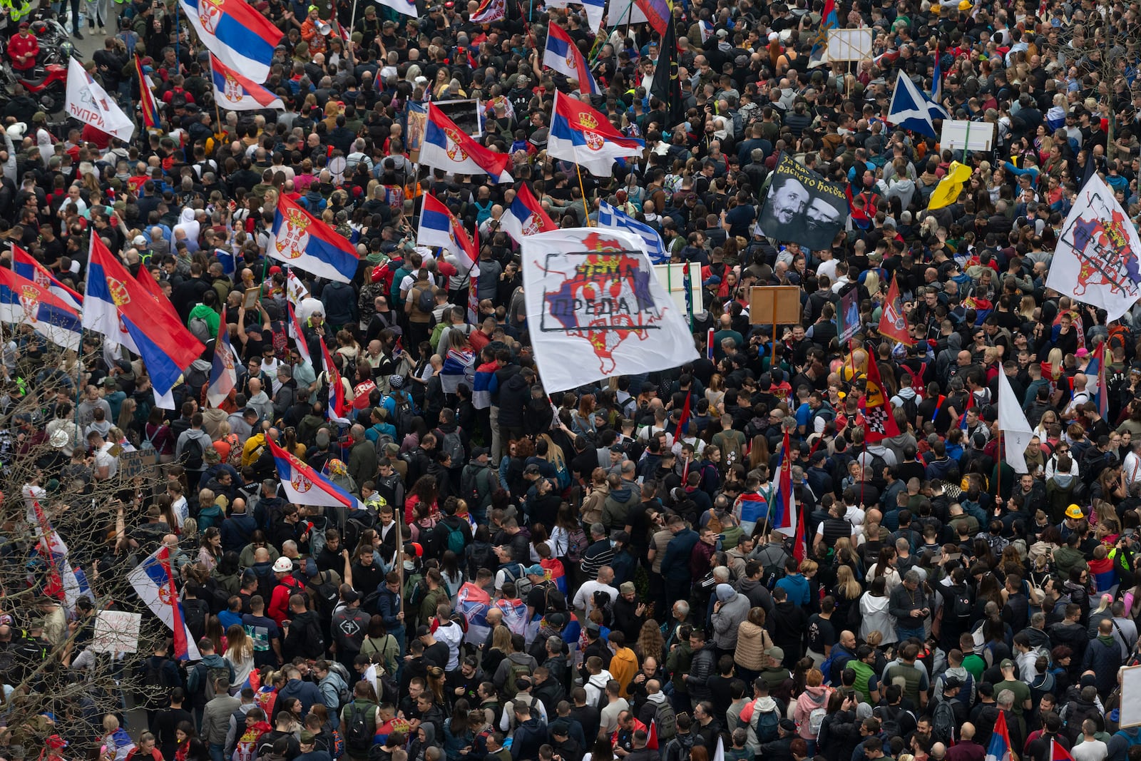 Protesters wave Serbian flags as they gather close to the Serbian parliament during a major anti-corruption rally led by university students in Belgrade, Serbia, Saturday, March 15, 2025. (AP Photo/Marko Drobnjakovic)