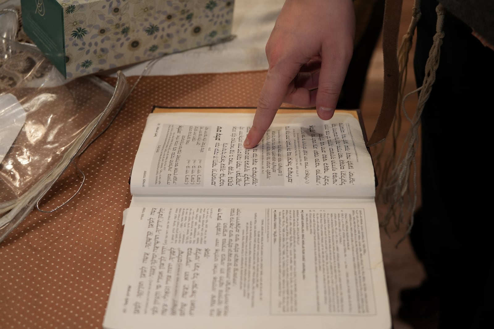 Dov Marcus points to prayers as he reads from the Jewish prayer book in Teaneck, N.J., on Friday, Dec. 20, 2024. (AP Photo/Luis Andres Henao)