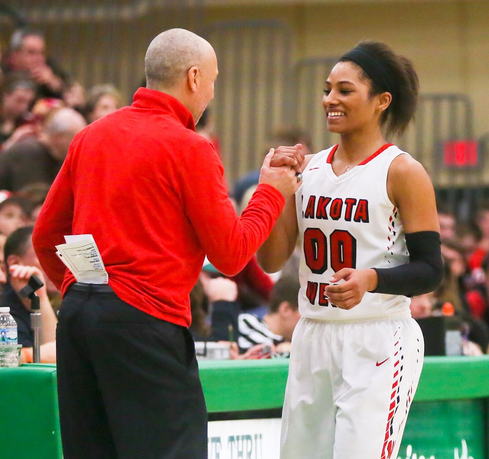 Lakota West guard Danielle Wells (00) is greeted by coach Andy Fishman during the final seconds of their Division I district championship win over Tecumseh at Harrison on Feb. 27, 2016. GREG LYNCH/STAFF