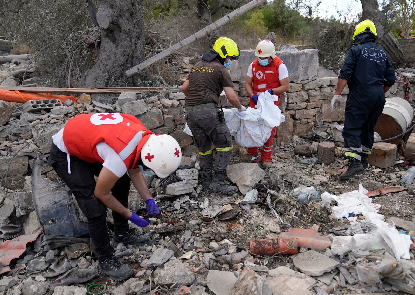 Lebanese Red Cross volunteers and Civil Defence workers remove the remains of killed people from the rubble of a destroyed building at the site of Monday's Israeli airstrike in Aito village, north Lebanon, Tuesday, Oct. 15, 2024. (AP Photo/Hussein Malla)