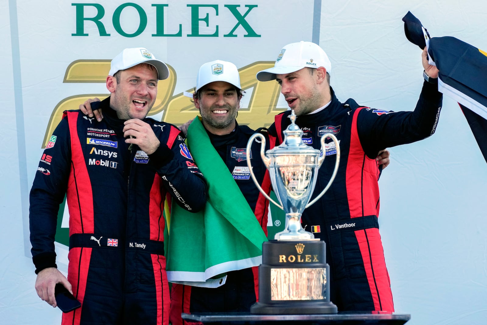 Porsche Penske Motorsport team members, from left to right, Britain's Nick Tandy, Brazil's Felipe Nasr and Belgium's Laurens Vanthoor celebrate after winning the IMSA Rolex 24 hour auto race at Daytona International Speedway, Sunday, Jan. 26, 2025, in Daytona Beach, Fla. (AP Photo/John Raoux)