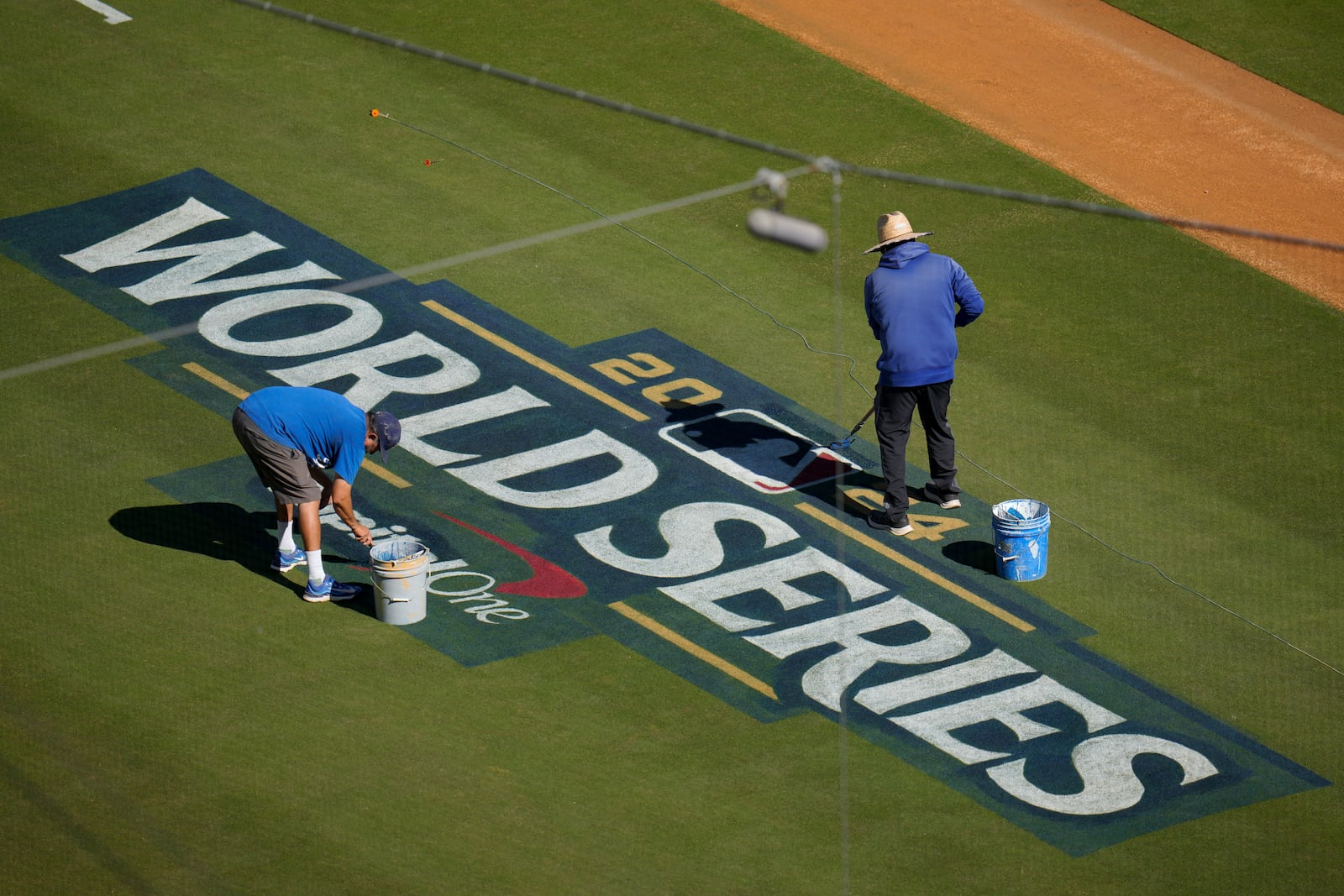 Workers prepare the field for the baseball World Series between the Los Angeles Dodgers and the New York Yankees, Thursday, Oct. 24, 2024, in Los Angeles. (AP Photo/Julio Cortez)