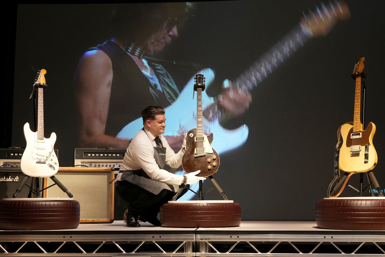 An art handler displays a displays a Gibson, Kalamazoo, Michigan, 1954 and 1972, a Solid-Body Electric Guitar, Les Paul, known as 'The Oxblood' at the Jeff Beck The Guitar Collection ahead of the pre-sale exhibition at Christie's auction rooms in London, Tuesday, Jan. 14, 2025. (AP Photo/Kirsty Wigglesworth)