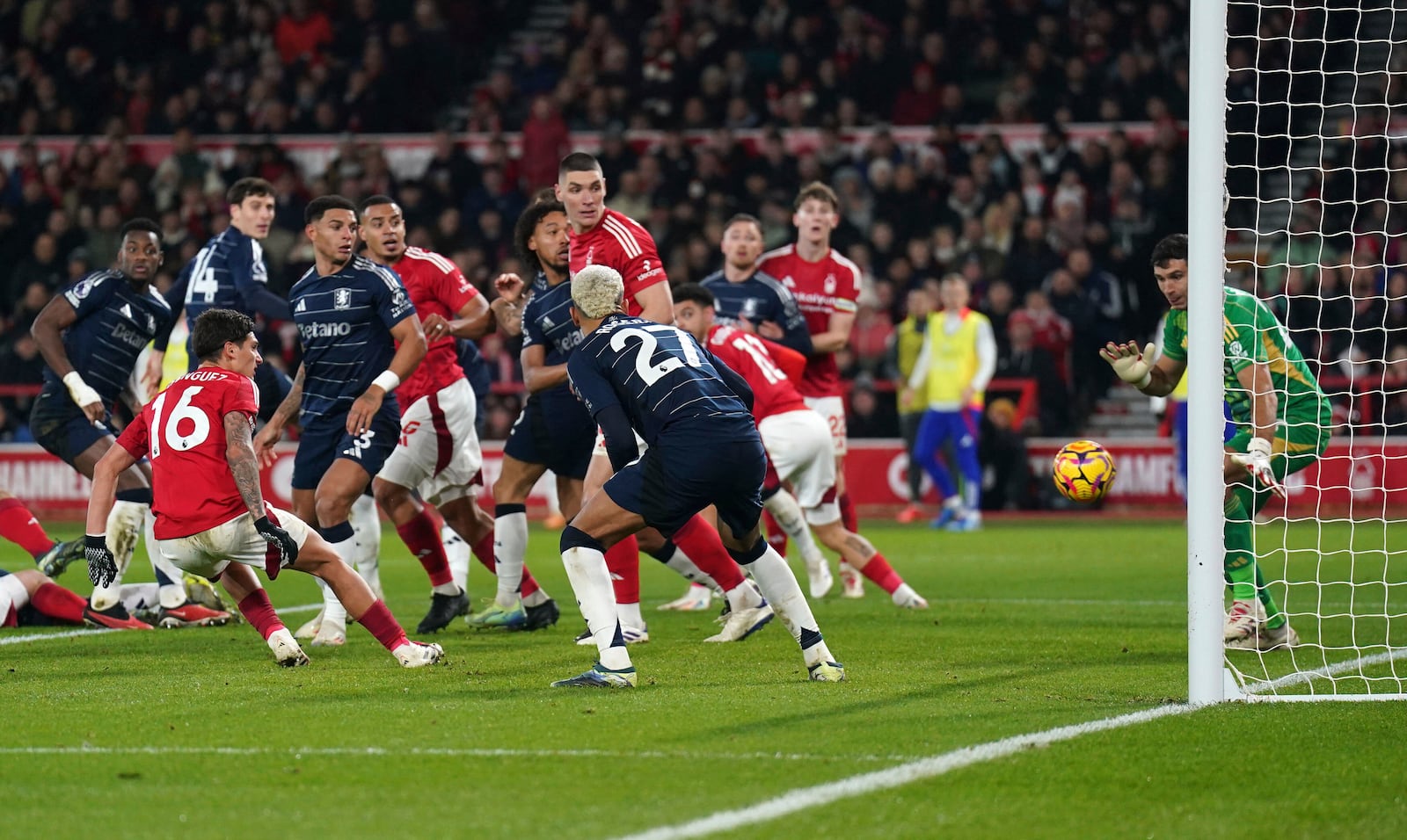 Aston Villa goalkeeper Emiliano Martinez, right, makes a save against Nottingham Forest's Nicolas Dominguez (16) during a Premier League soccer match at the City Ground, Saturday Dec 14, 2024, in Nottingham, England. (Joe Giddens/PA via AP)