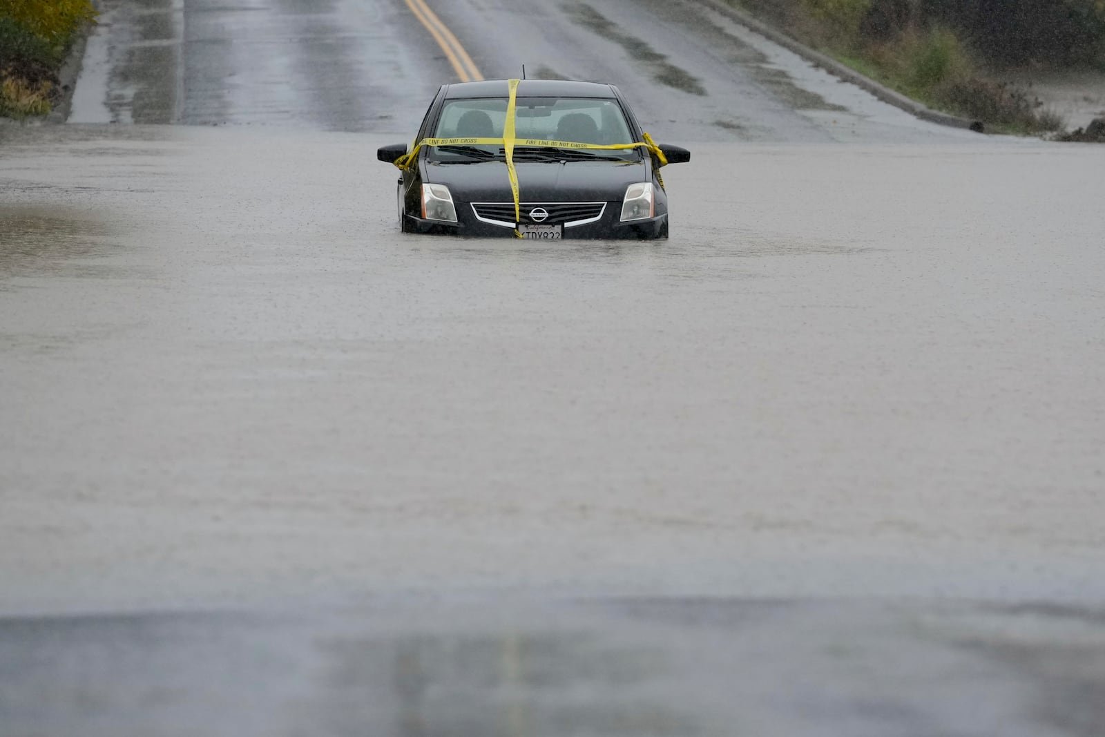 A car is left stranded on a flooded road during a storm Thursday, Nov. 21, 2024, in Windsor, Calif. (AP Photo/Godofredo A. Vásquez)