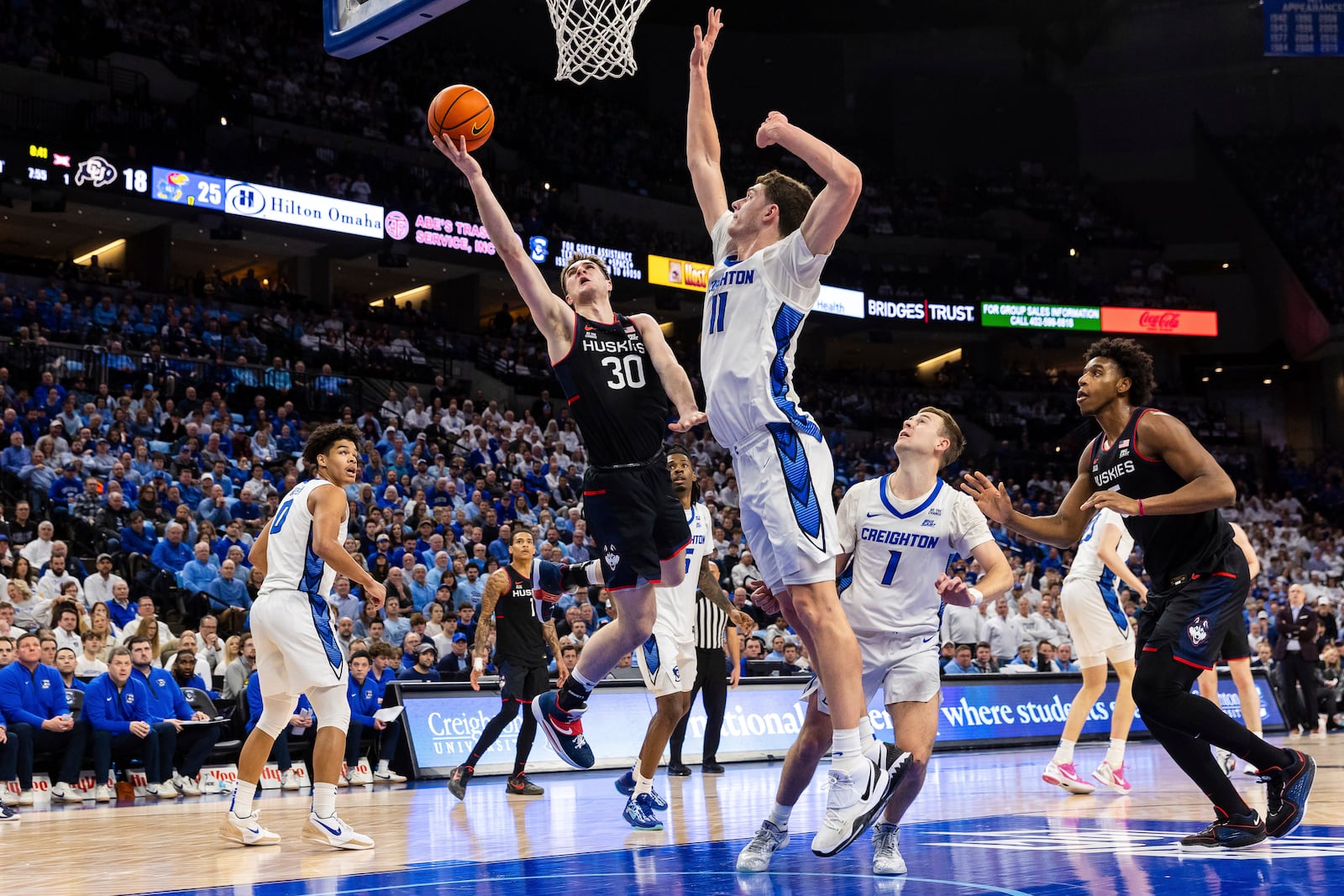 UConn forward Liam McNeeley (30) goes up for a layup against Creighton center Ryan Kalkbrenner (11) during the first half of an NCAA college basketball game, Tuesday, Feb. 11, 2025, in Omaha, Neb. (AP Photo/Bonnie Ryan)