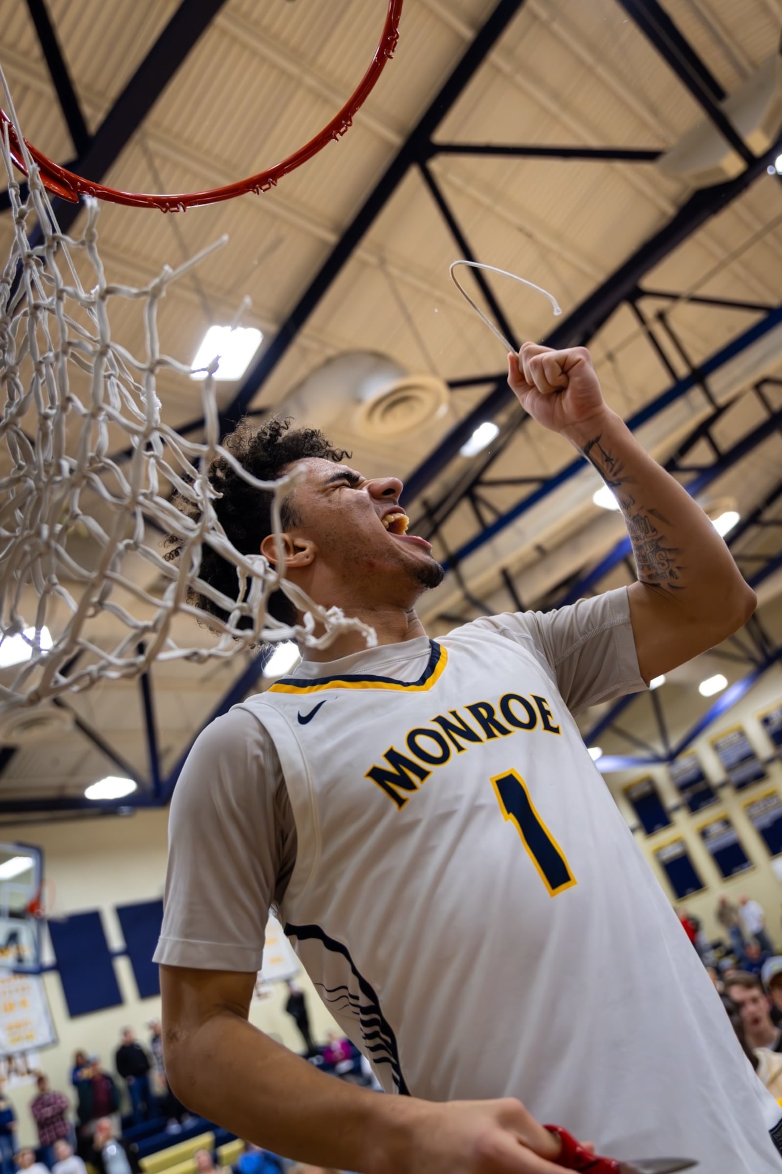 Monroe's A.J. Saunders (1) cuts down a piece of the net after the Hornets clinched at least a share of the Southwestern Buckeye League Southwestern Division title on Friday night. AJ Fullam/CONTRIBUTED