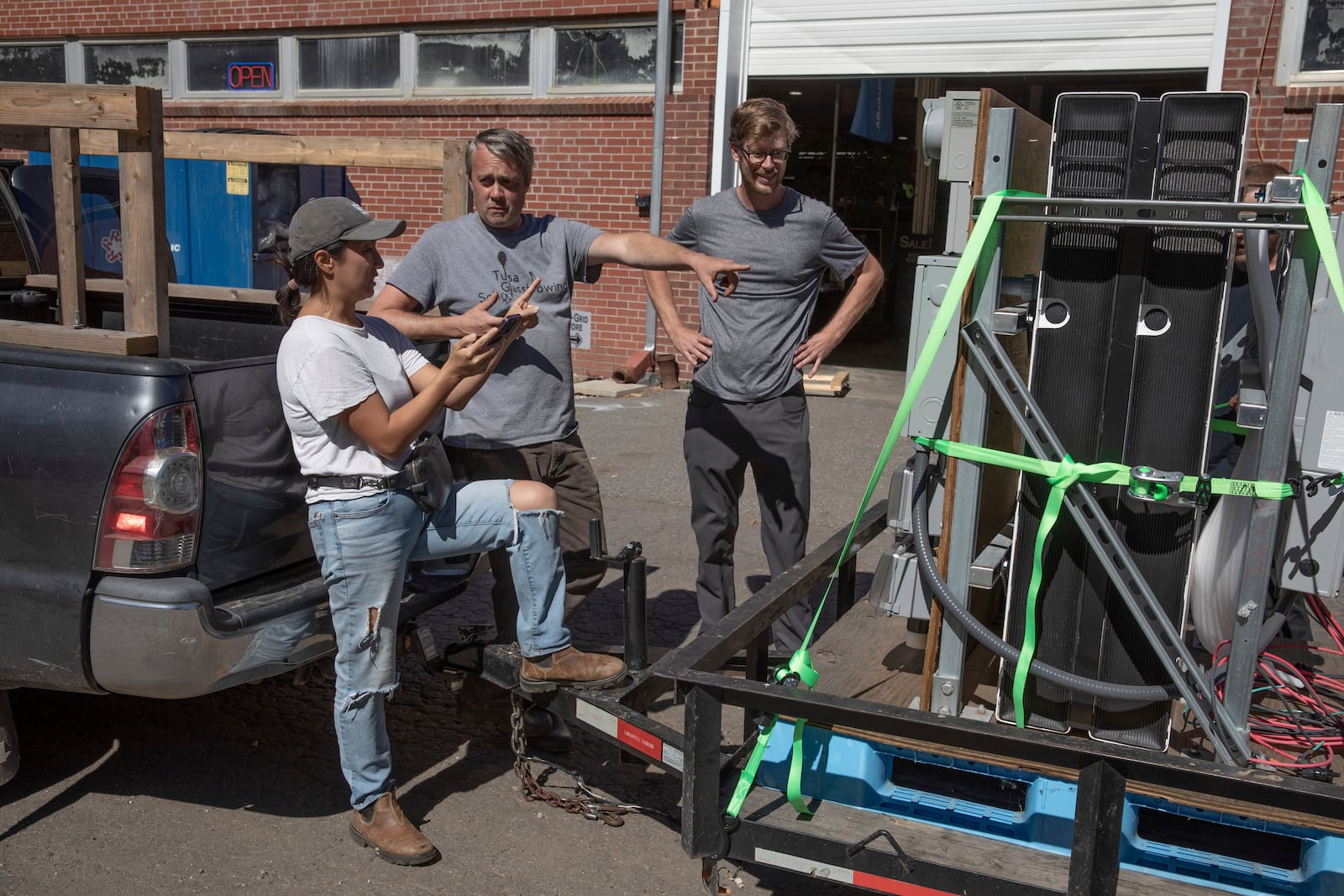 Footprint Project co-founder Jamie Swezey, left, volunteer Hayden Wilson, center, and co-founder Will Heegaard, right, review the delivery schedule before taking mobile power units to Helene-impacted communities in Mars Hill, N.C. on Oct. 9, 2024. (AP Photo/Gabriela Aoun Angueria)