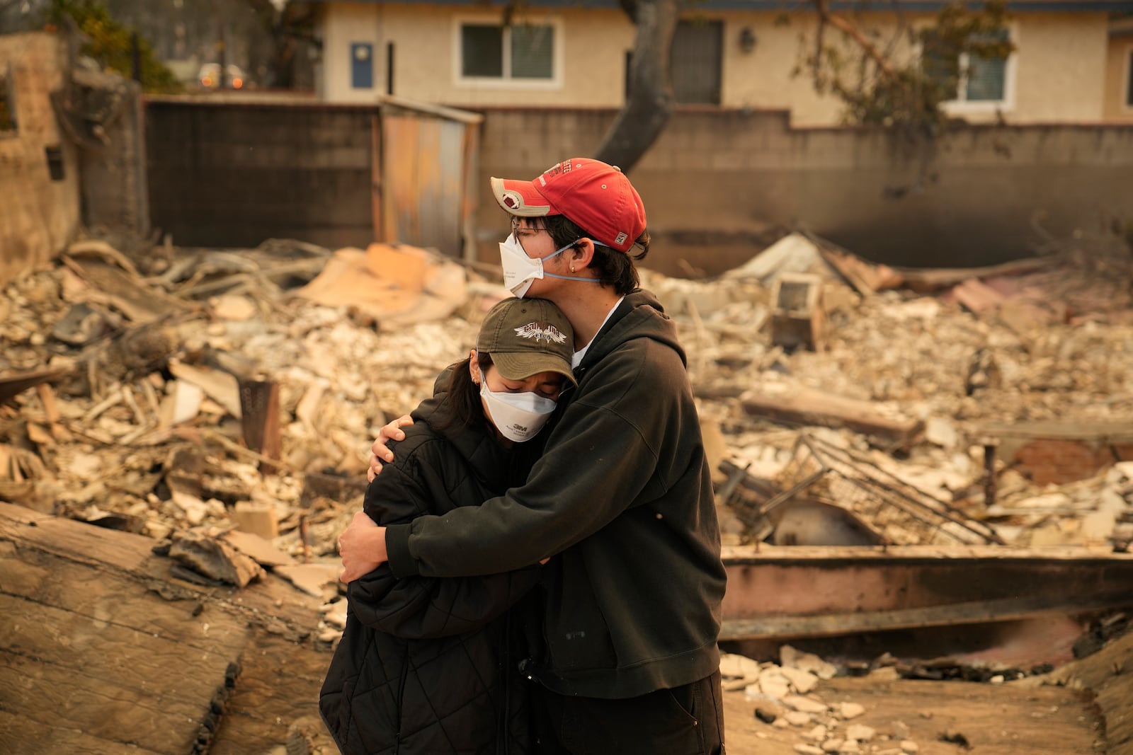 Ari Rivera, right, and Anderson Hao and woman hold each other in front of their destroyed home in Altadena, Calif., Thursday, Jan. 9, 2024. (AP Photo/John Locher)