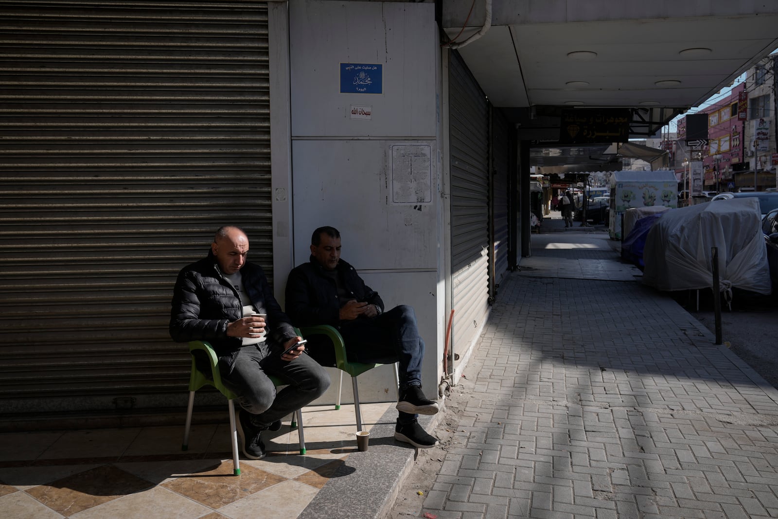 Palestinians sit in front of closed shops during a general strike called as Palestinian security forces mount a major raid against militants in the Jenin refugee camp in the Israeli-occupied West Bank, Monday, Dec. 23, 2024. (AP Photo/Majdi Mohammed)