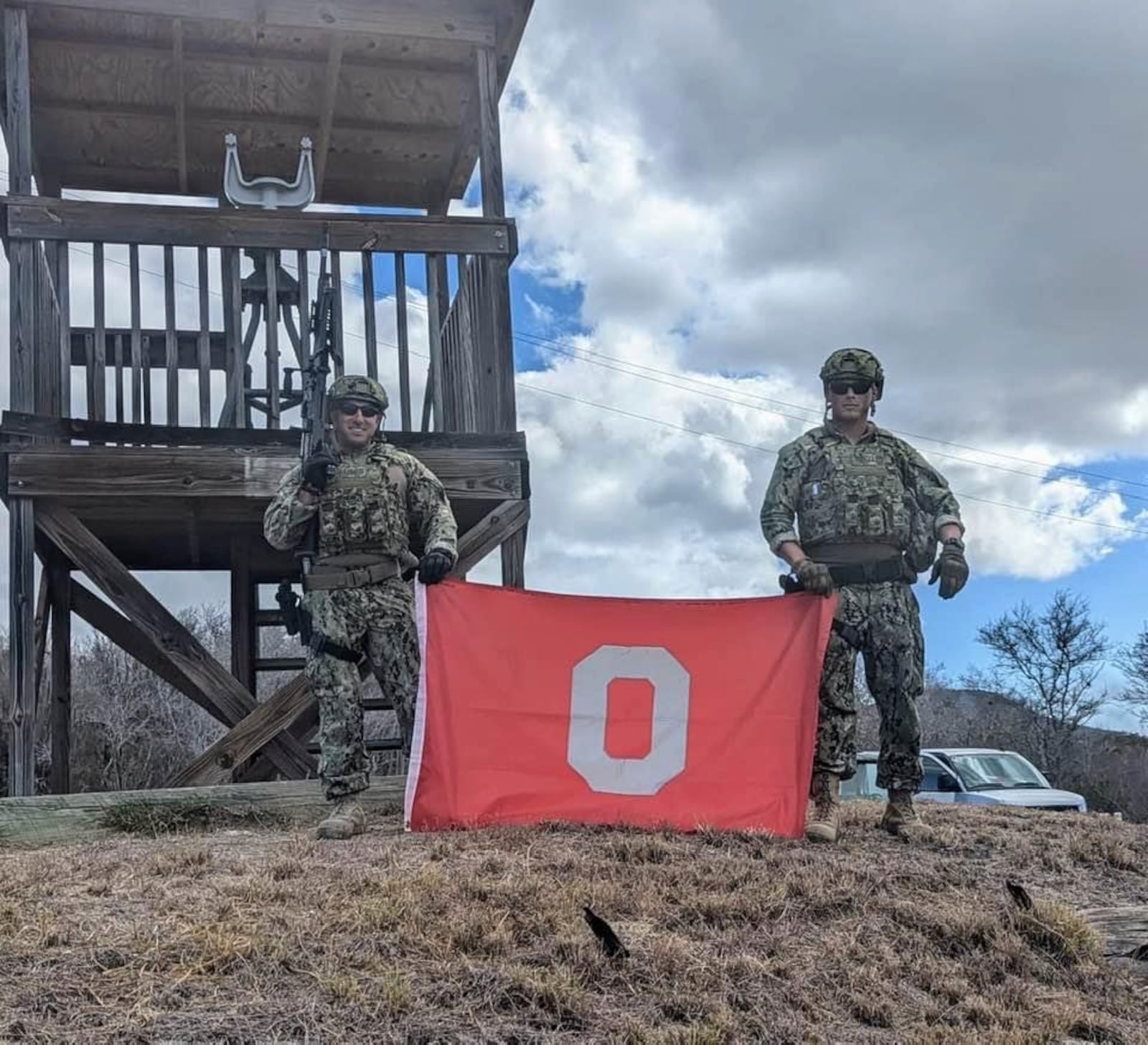 Tyler Good, right, of Waynesville, poses for a photo with the Ohio State flag with working in the Coast Guard as a Company Commander. This photo is from his tour at Guantanamo Bay, Cuba. Contributed photo