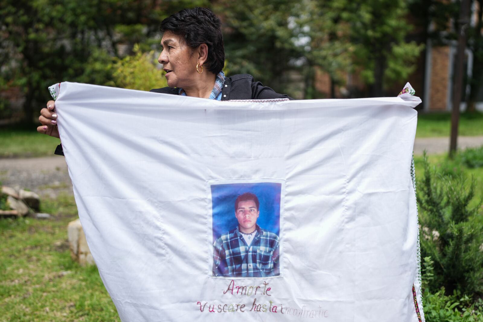 Doris Tejada holds a sheet covered with a photograph of her missing son, Oscar Morales, in Bogota, Colombia, Tuesday, Nov. 5, 2024. Tejeda said Morales disappeared in 2007 near the Venezuelan border, becoming a "false positive," a civilian intentionally registered as a rebel and slain by the military. (AP Photo/Ivan Valencia)