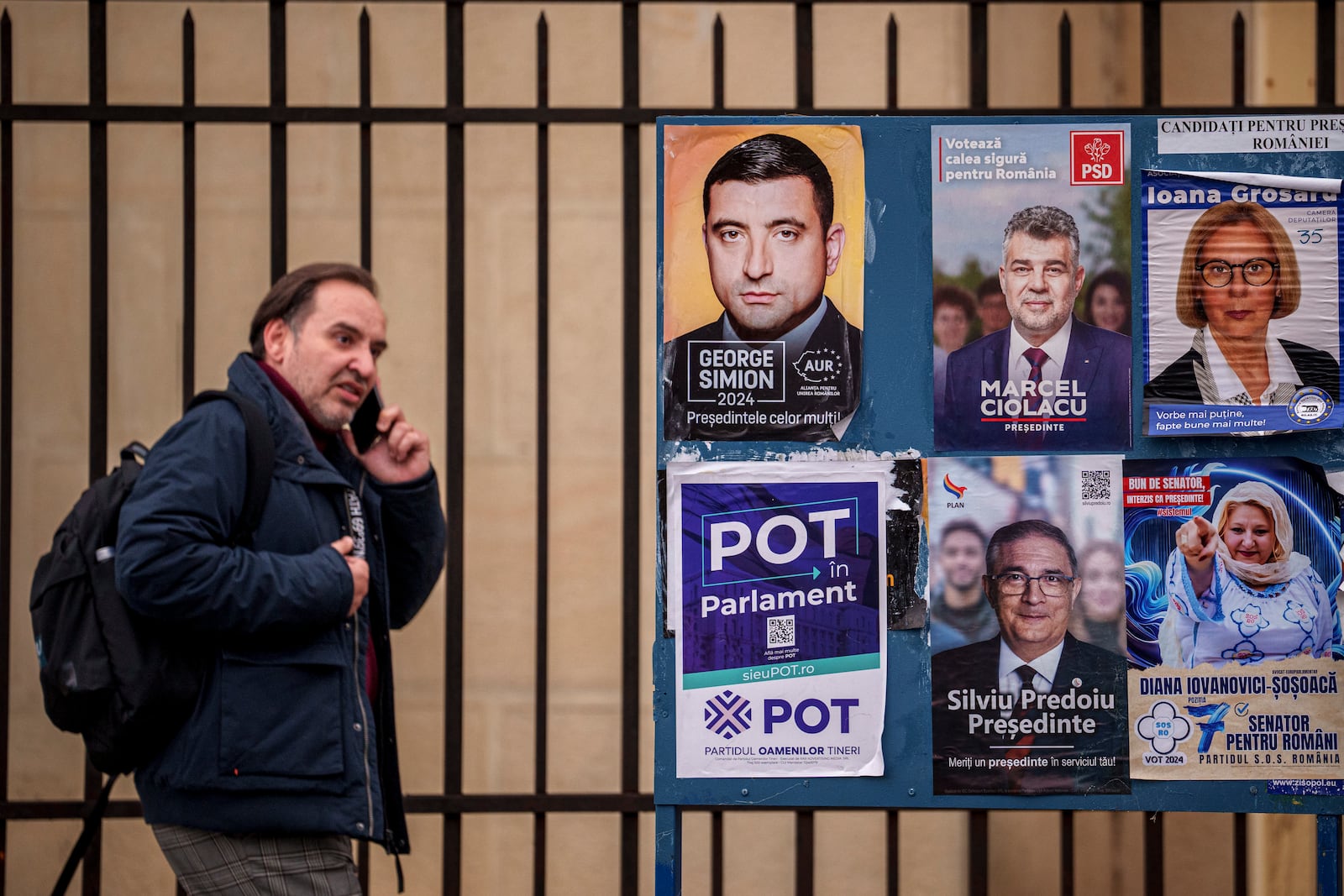 A man walks by panels displaying electoral posters ahead of the Nov. 24 presidential elections in Bucharest, Romania, Friday, Nov. 22, 2024. (AP Photo/Andreea Alexandru)