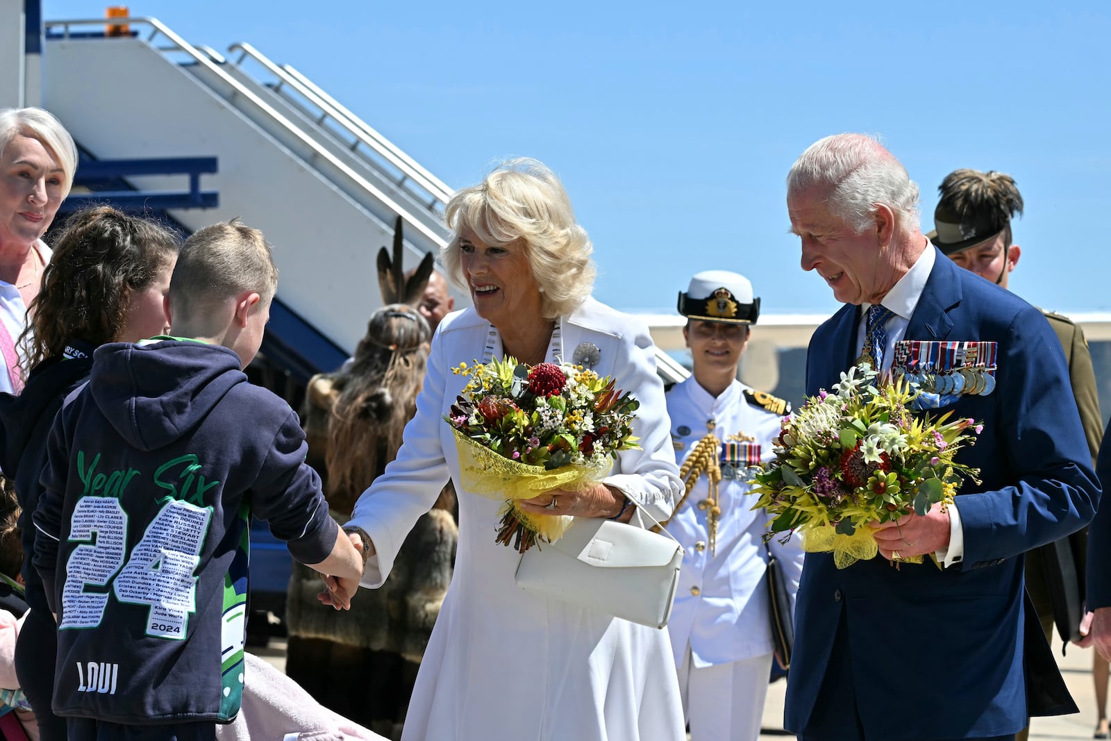 Britain's King Charles III and Queen Camilla receive flowers after arriving at Defence Establishment Fairbairn in Canberra, Australia, Monday, Oct. 21, 2024. (Saeed Khan/ Pool Photo via AP)