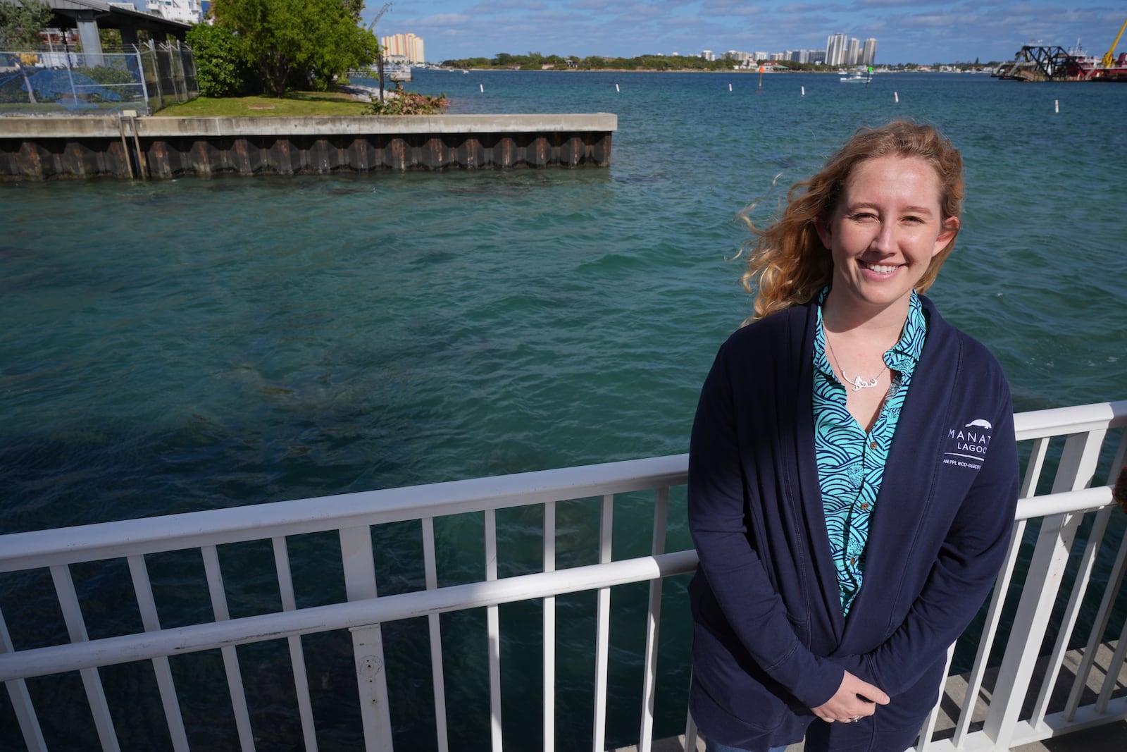 Rachel Shanker, education manager for Florida Power & Light Company's Manatee Lagoon, poses for a picture beside waters where dozens of manatees gather in winter in the warm-water outflows of the company's power plant, in Riviera Beach, Fla., Friday, Jan. 10, 2025. (AP Photo/Rebecca Blackwell)