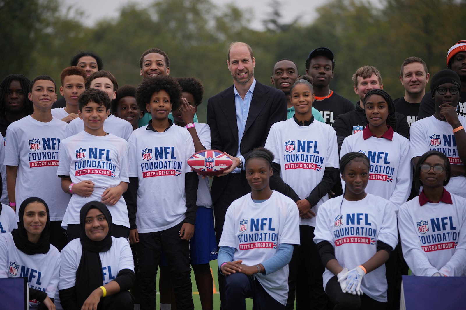 Britain's Prince William poses with participants he attends a NFL Foundation NFL Flag event, an inclusive and fast paced American Football format, in London, Tuesday, Oct. 15, 2024. (AP Photo/Kin Cheung, Pool)