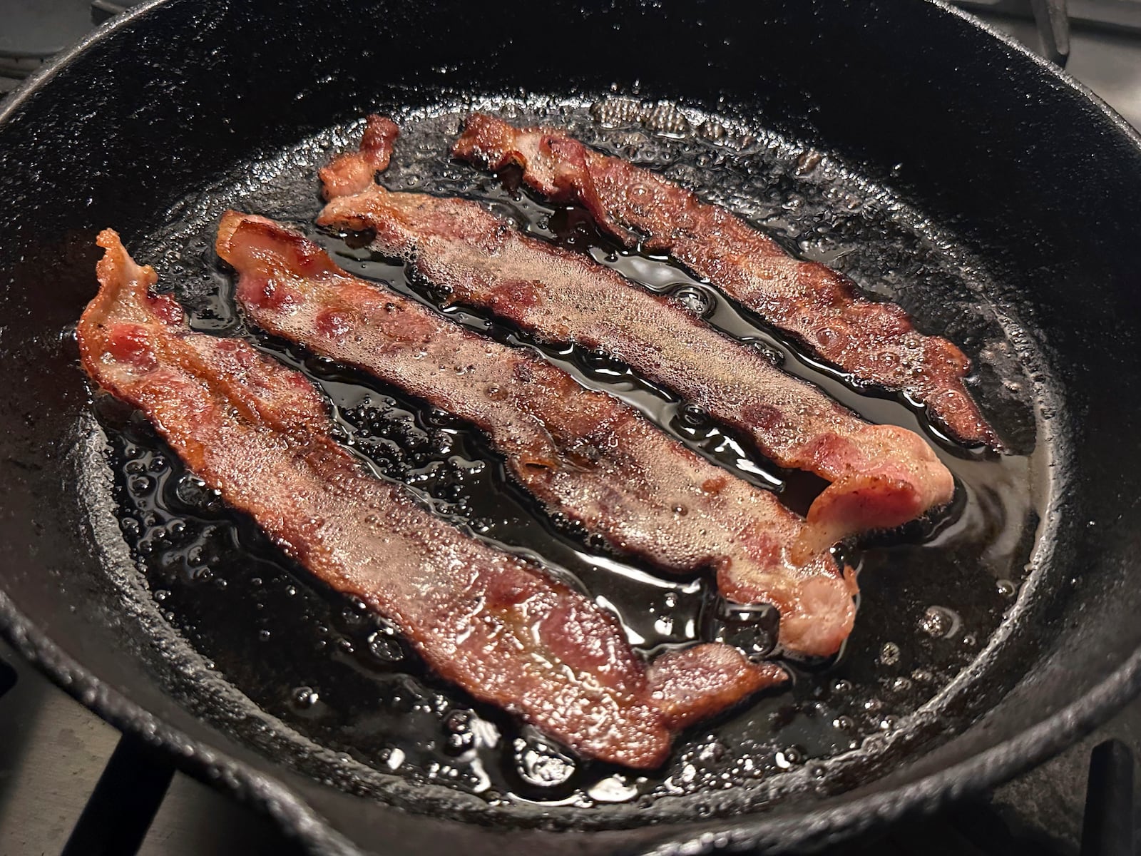 Bacon cooks in a cast iron pan on Monday, Oct. 7. 2024. in New York. (AP Photo/Richard Drew)